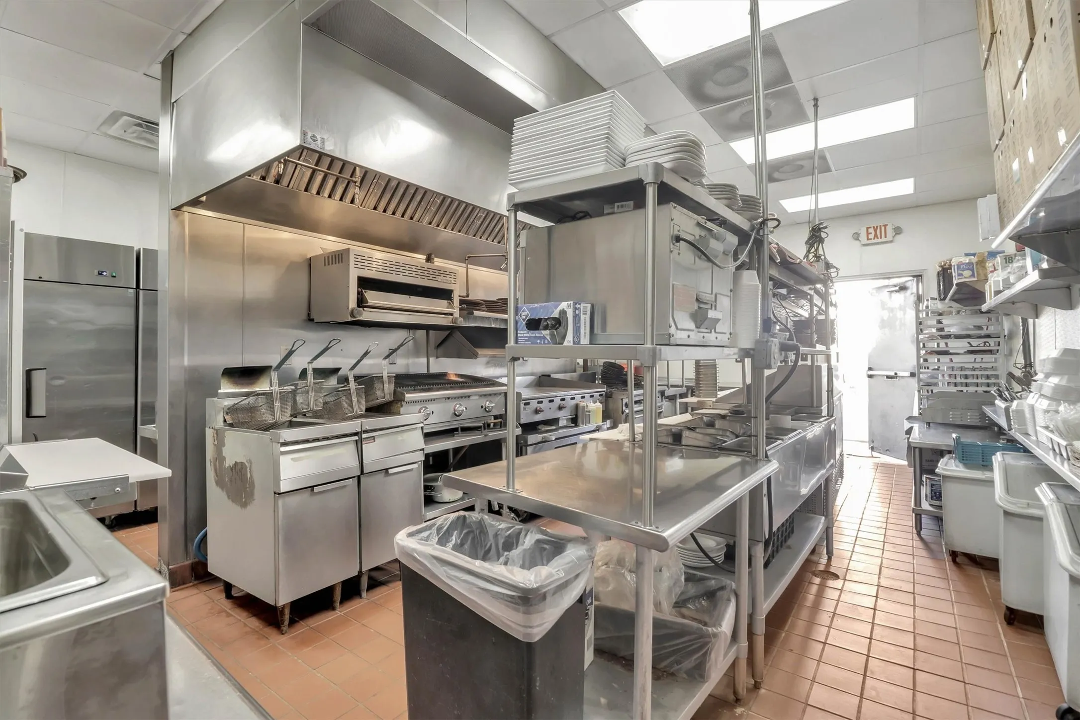 Commercial kitchen featuring stainless steel appliances, extensive stainless steel shelving, and durable tiled flooring