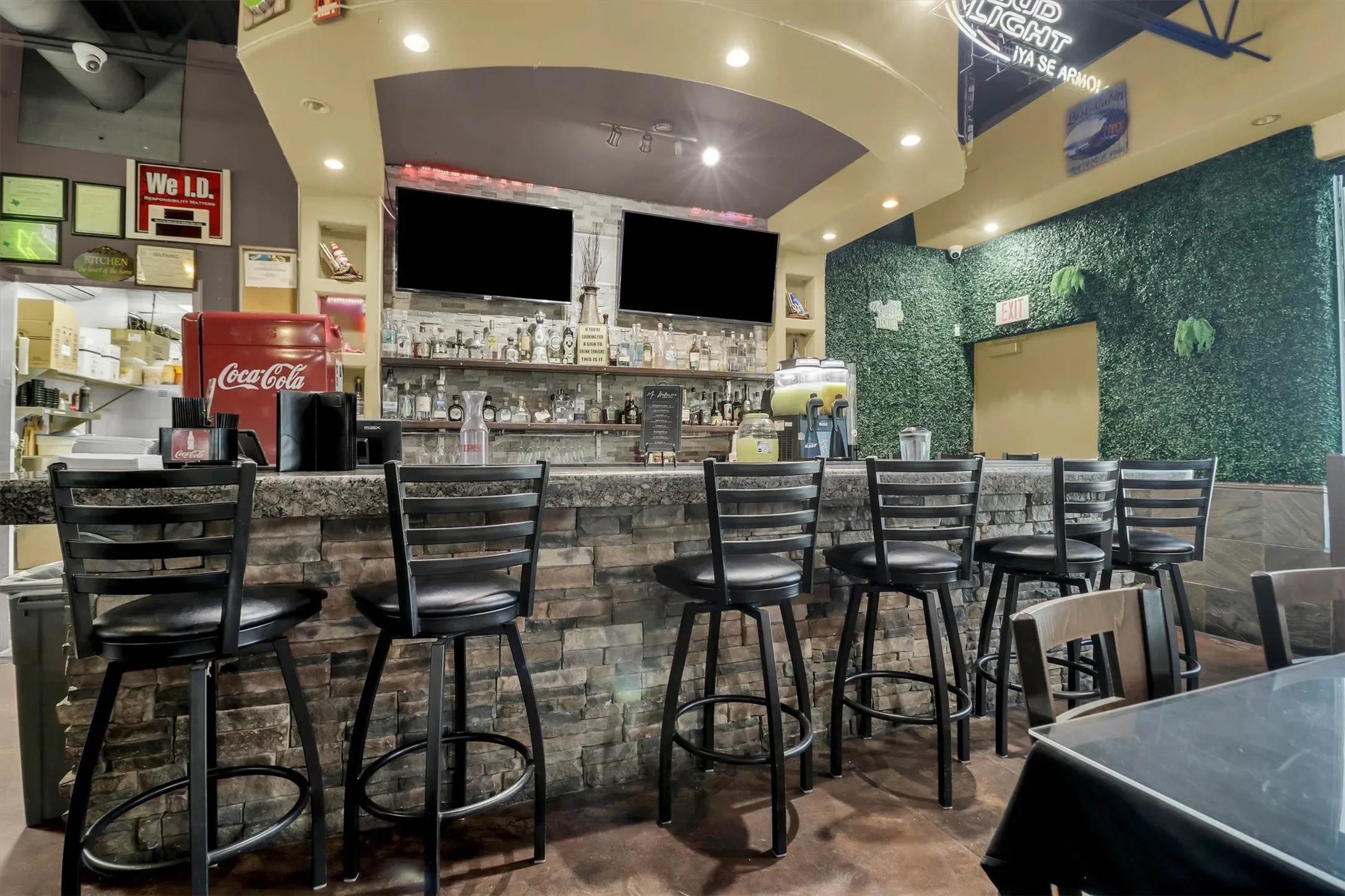 Stone-clad bar featuring multiple stools and a full back bar with shelving