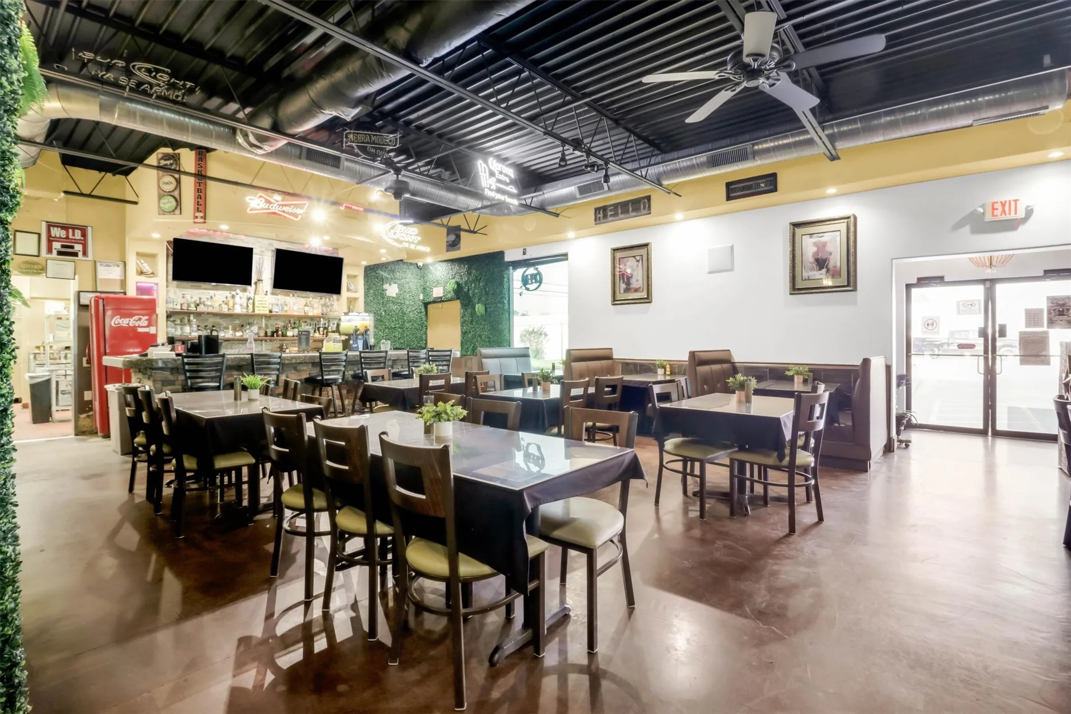 Spacious commercial interior featuring a full-service bar area, multiple dining tables, booths, and exposed ceiling ductwork