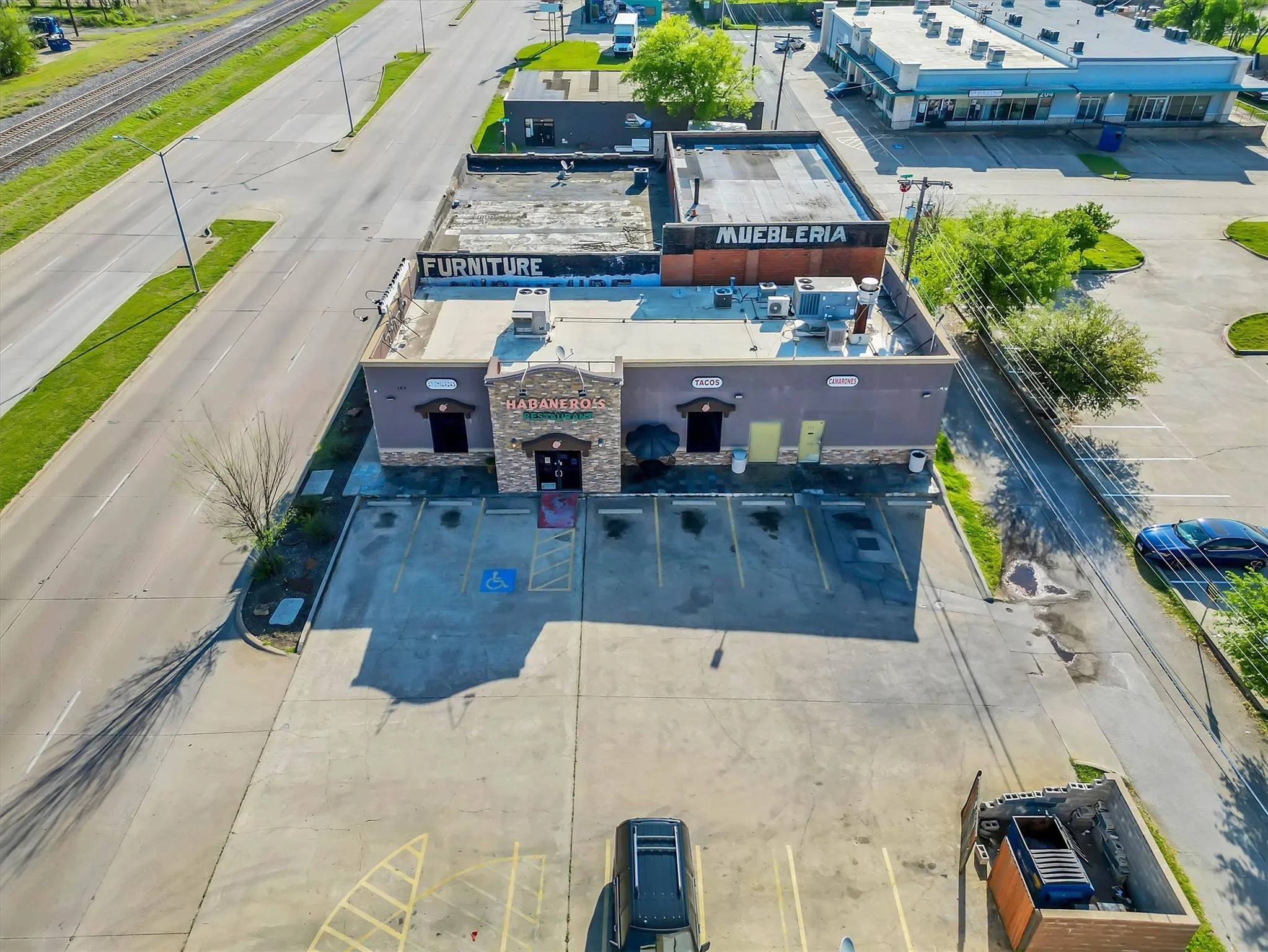 Commercial building featuring a stone facade entrance, flat roof, and an expansive paved parking lot