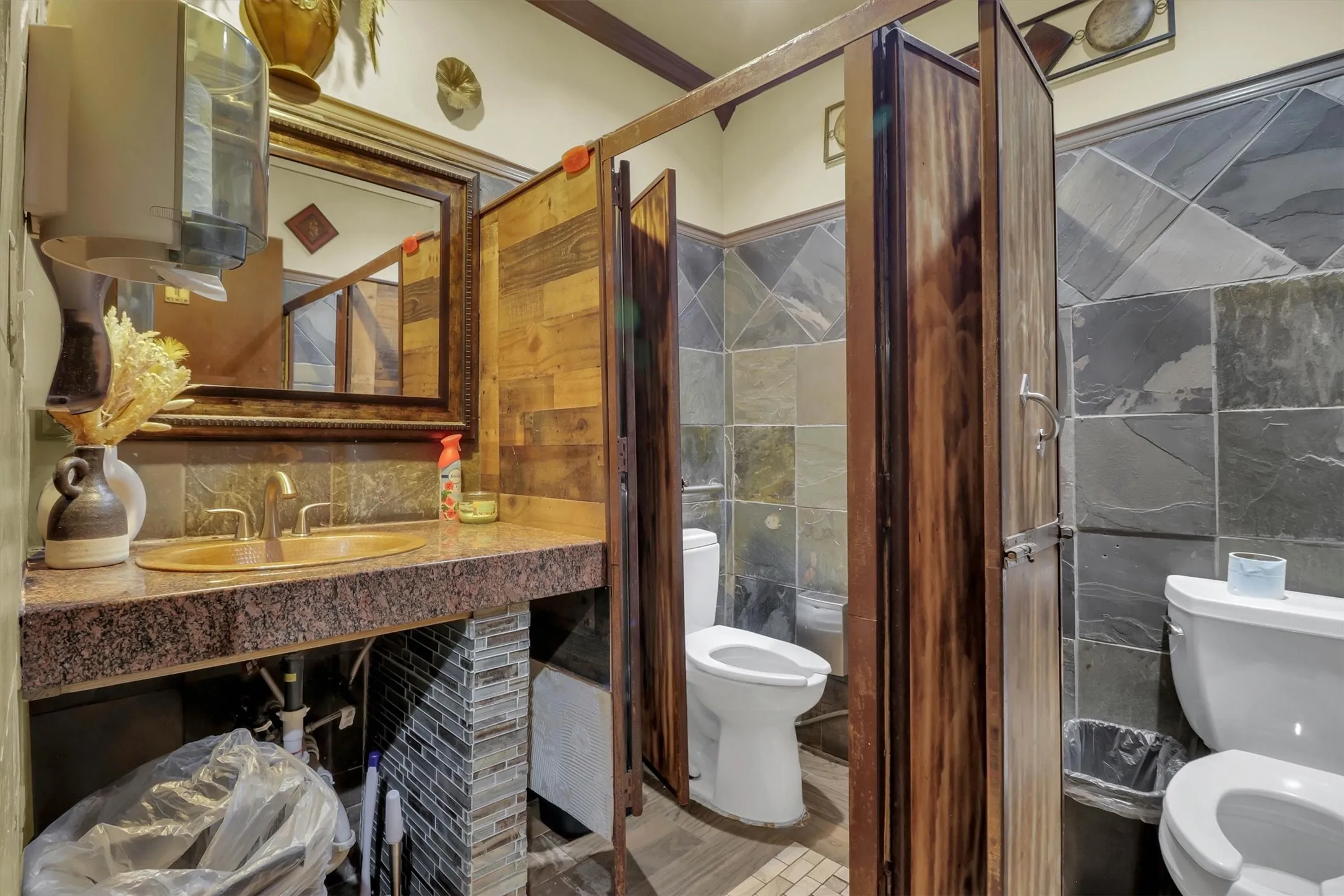 Restroom featuring an oval vessel sink, granite-style countertop, and ornate framed mirror