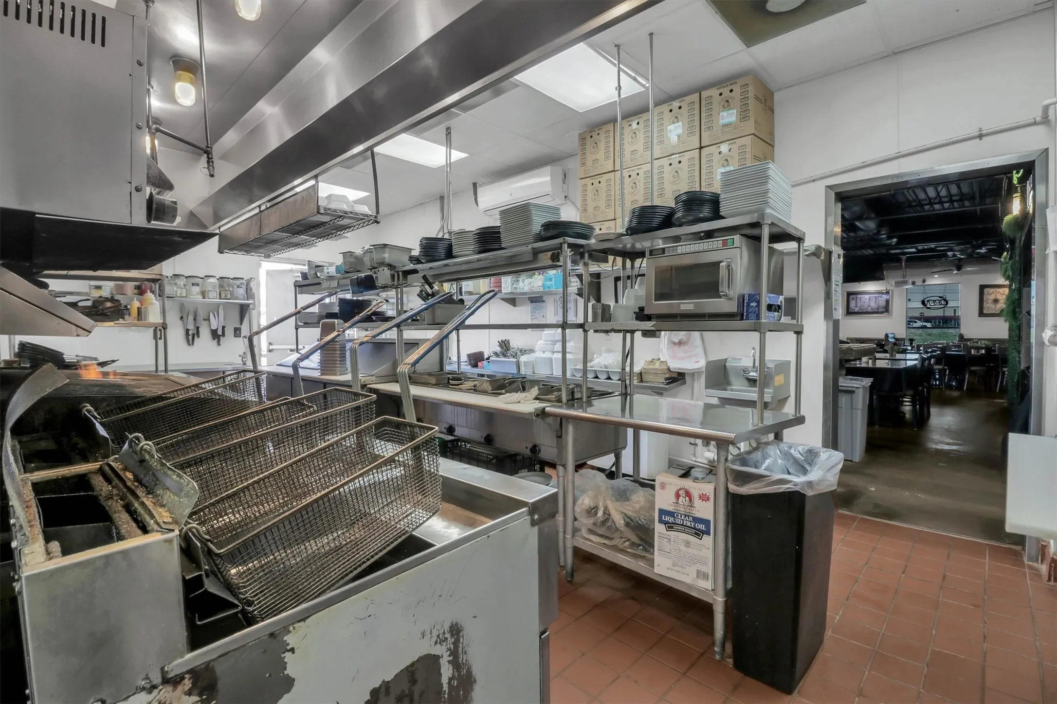 Commercial kitchen featuring stainless steel equipment, tiled flooring, and overhead lighting