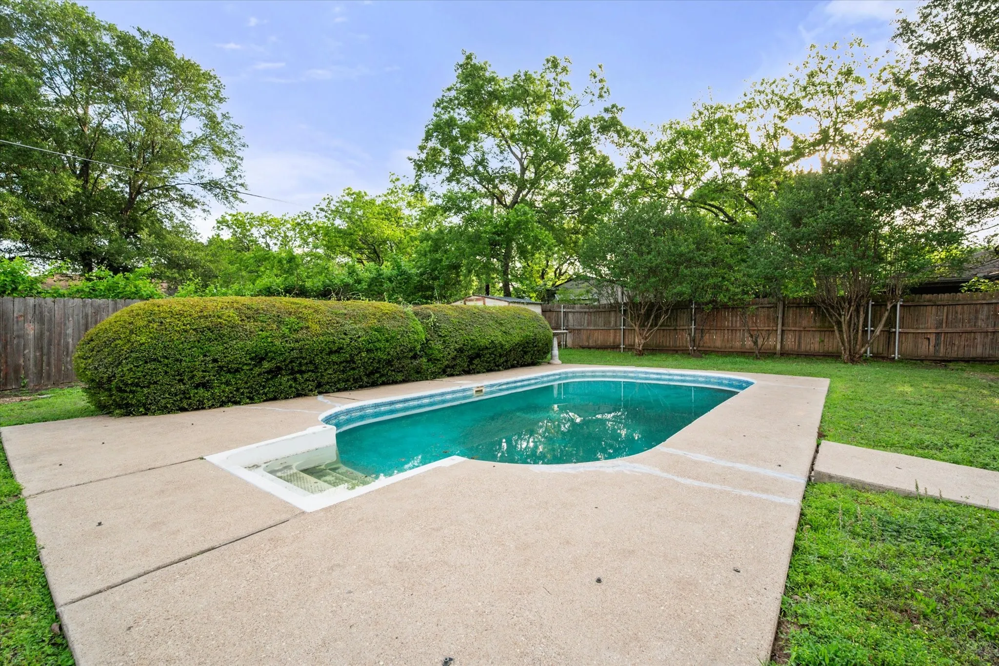Rectangular inground swimming pool with integrated steps, surrounded by concrete decking