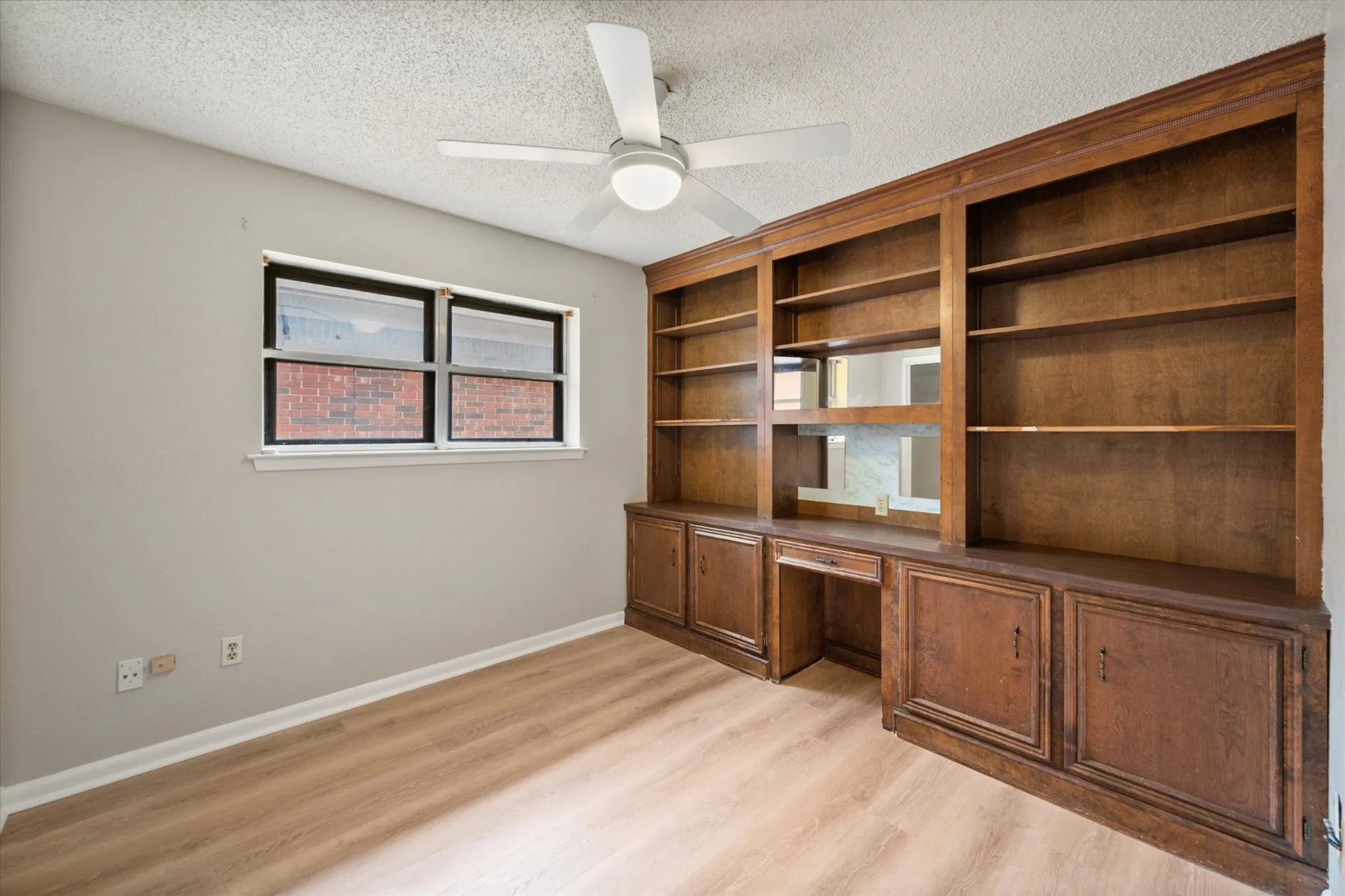 Room featuring extensive built-in wooden shelving and cabinetry with an integrated desk