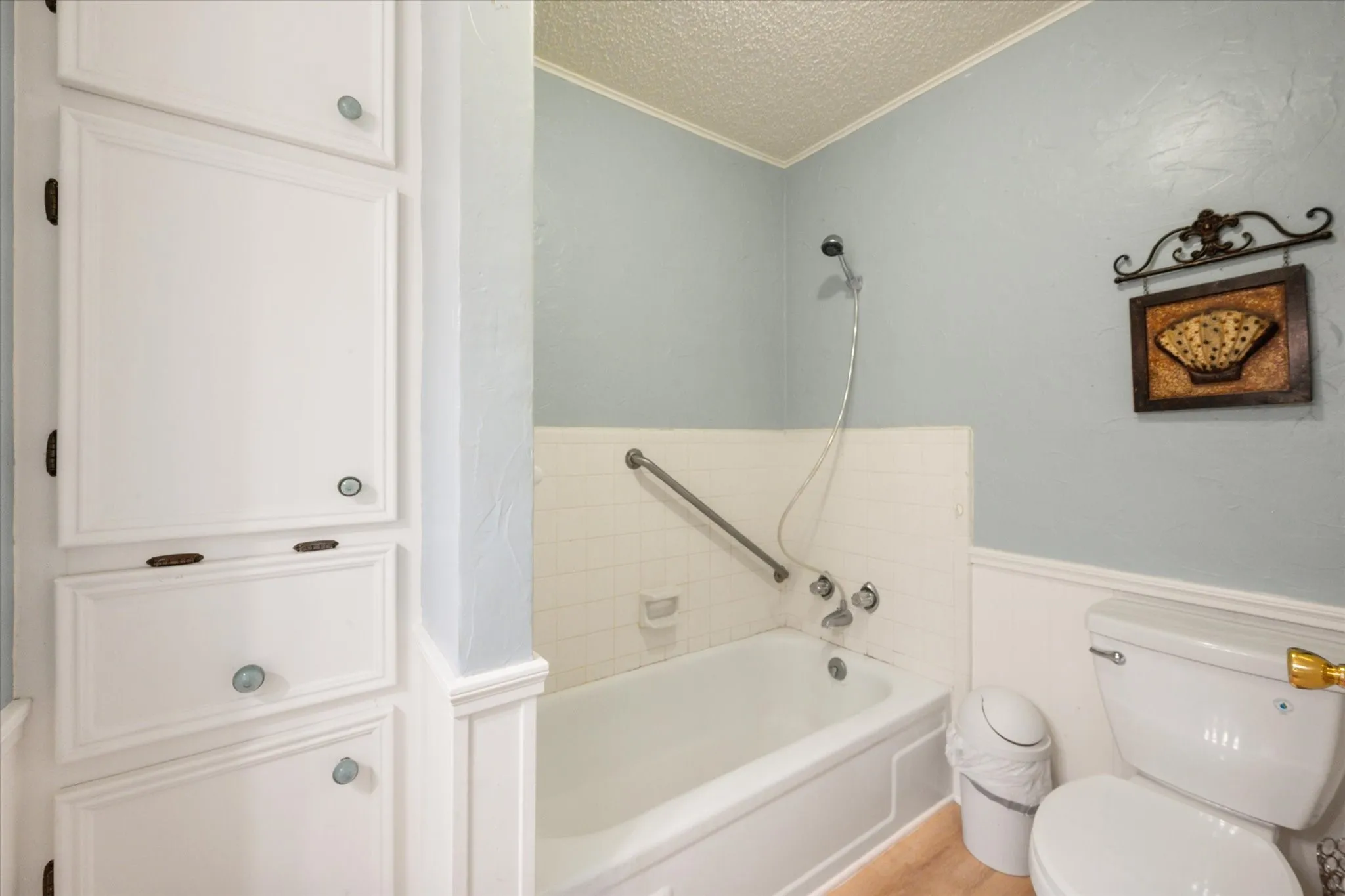 Bathroom featuring a white bathtub, white tile surround, and a chrome shower fixture