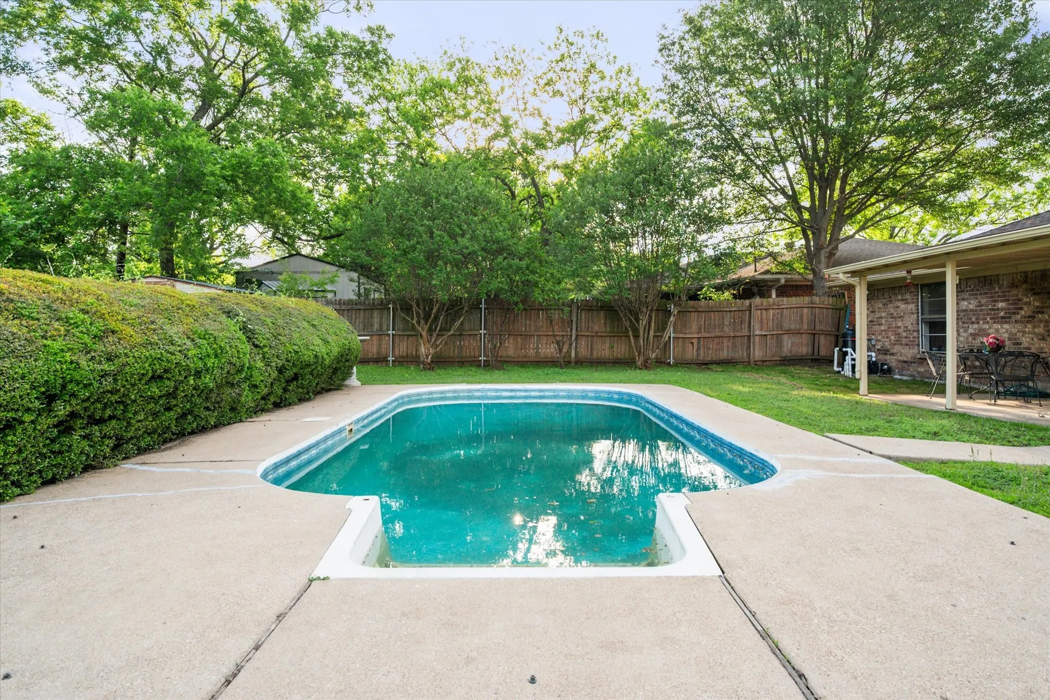 Backyard featuring an in-ground swimming pool with surrounding concrete decking