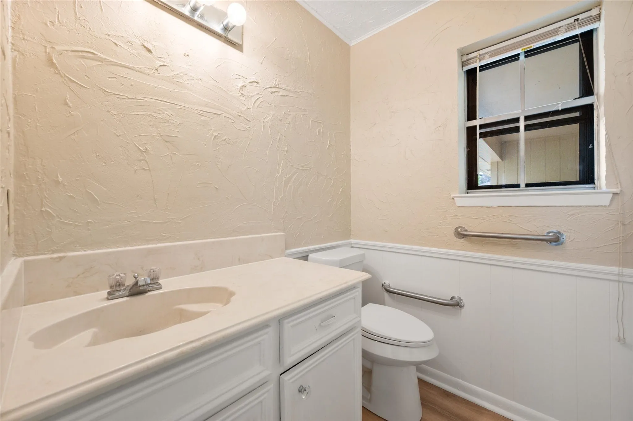 Bathroom vanity with an integrated sink, laminate countertop, and white cabinetry