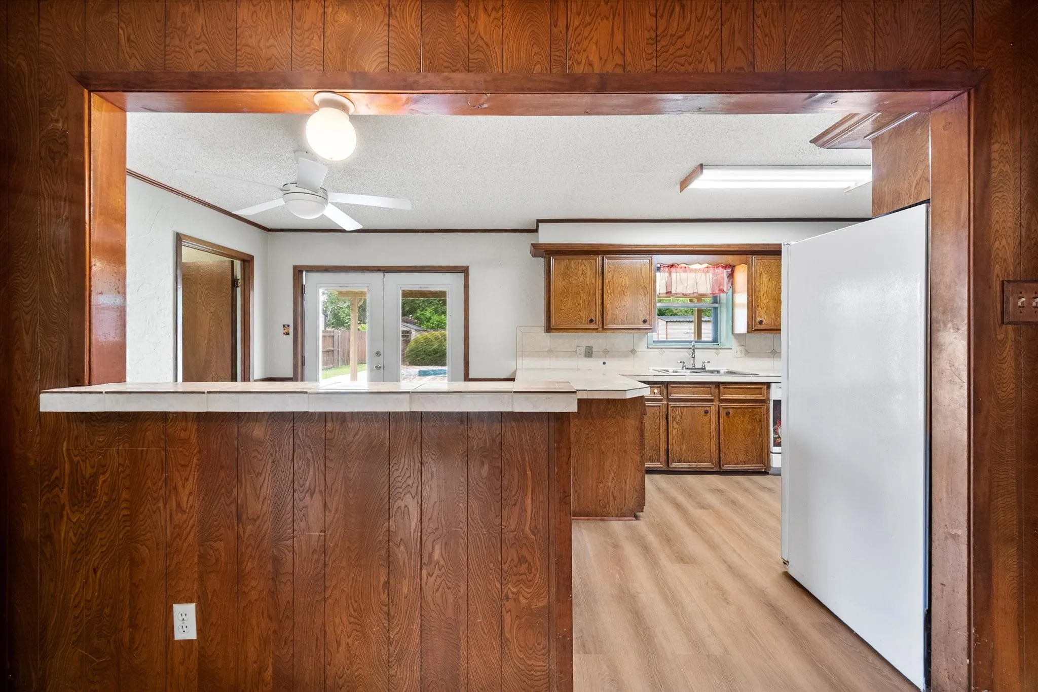 Wood-paneled pass-through bar area featuring a tile countertop