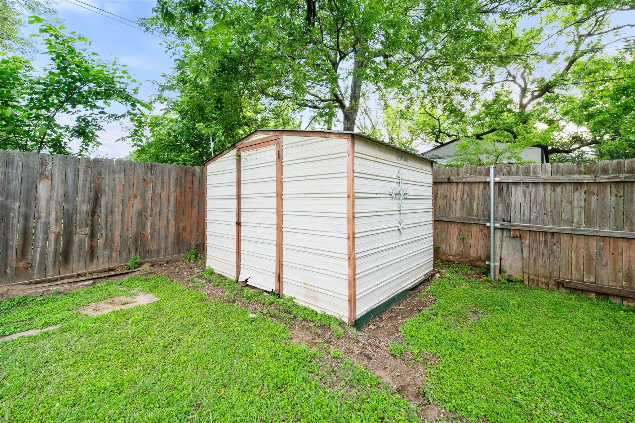Detached storage shed with a corrugated metal exterior, positioned on a grassy area