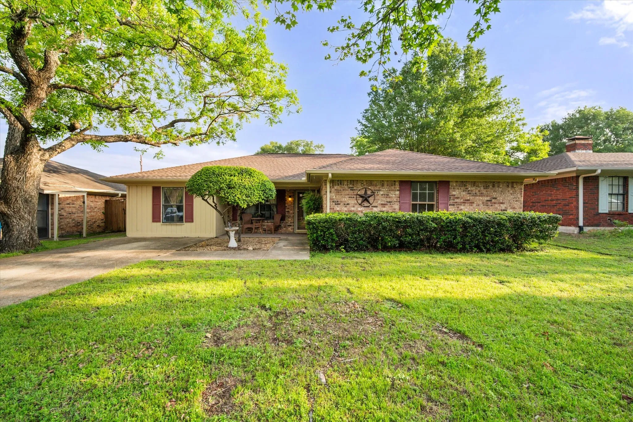 Brick facade home featuring a spacious front lawn and a mature shade tree