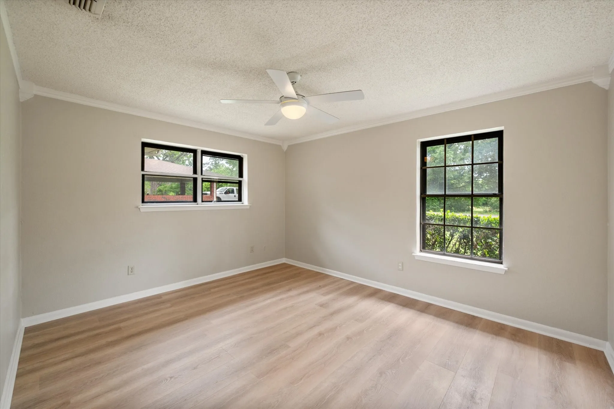 Interior room featuring light wood-finish flooring, neutral paint palette, and white crown molding