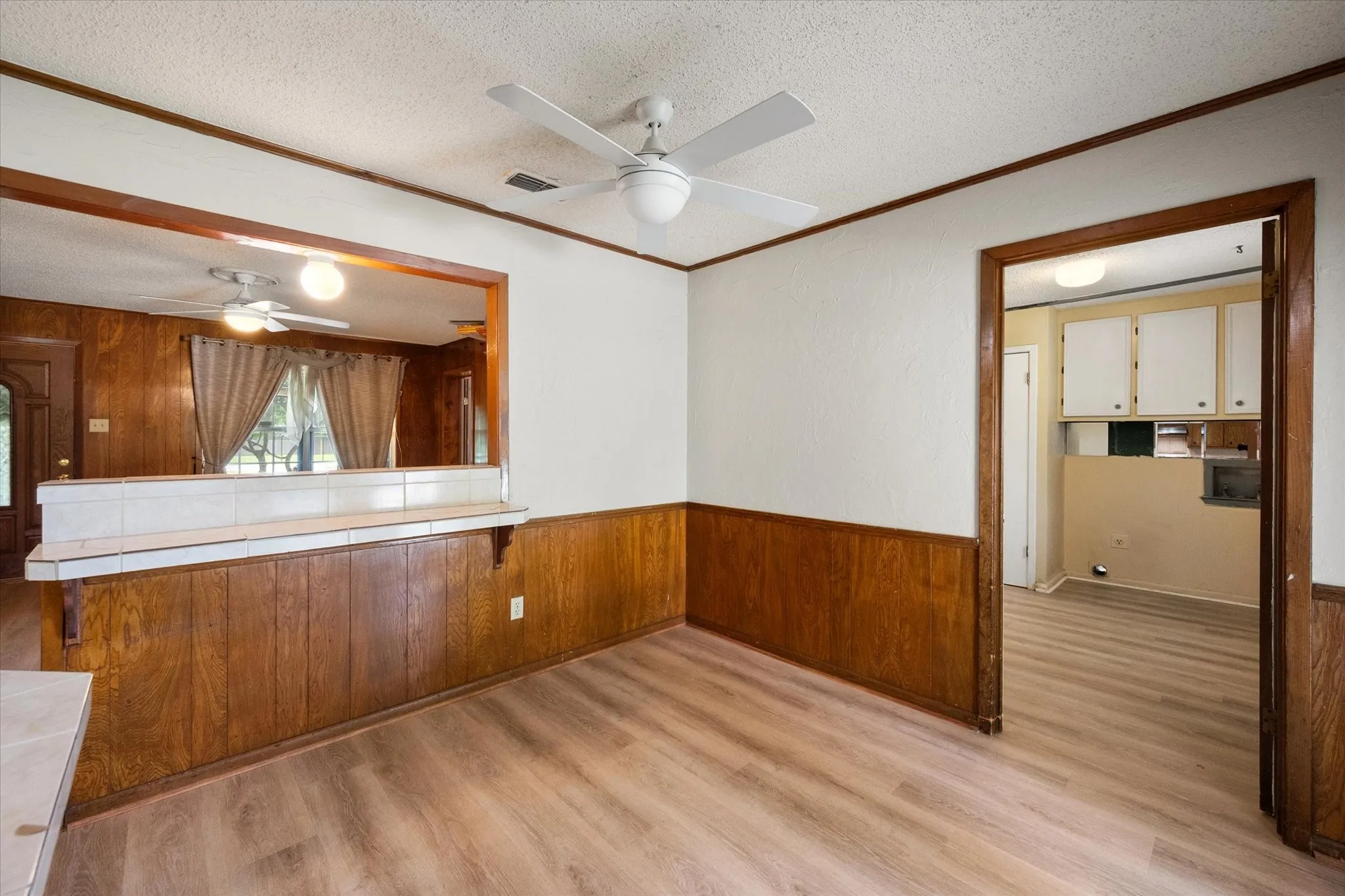Room featuring wood-finish flooring, white ceiling, and a white ceiling fan with integrated lighting