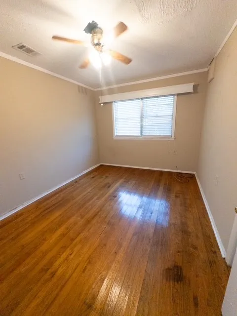 Hardwood flooring throughout featuring white baseboards, a ceiling fan with light fixture, and a window with horizontal blinds