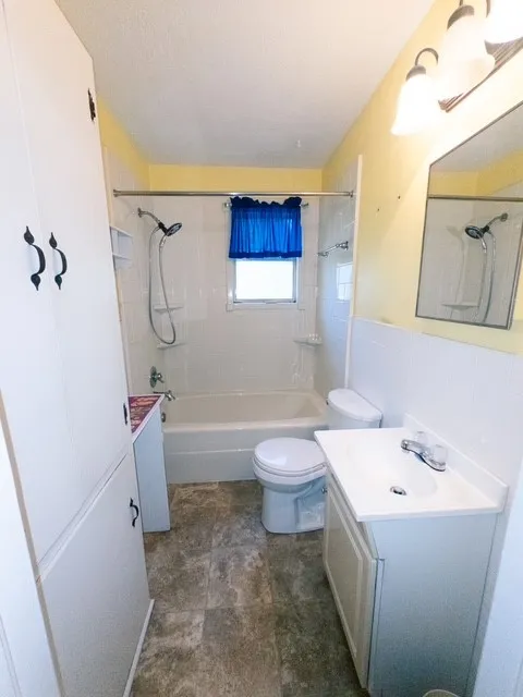 Bathroom featuring a white bathtub, ceramic tile surround, built-in storage cabinetry, and a vanity with an integrated sink