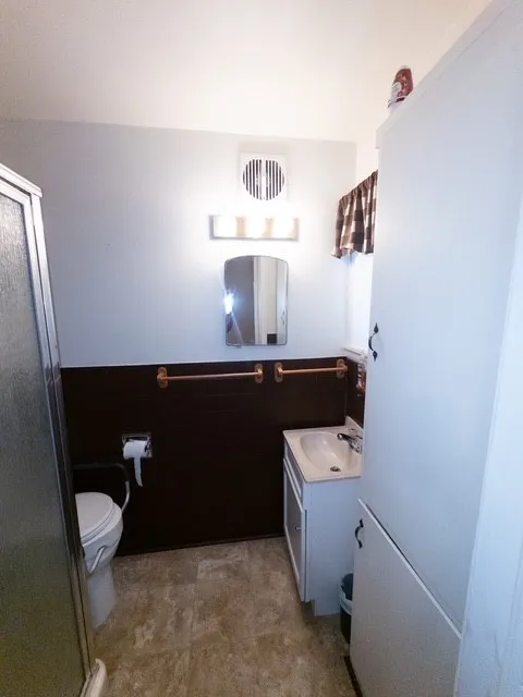 Full bathroom featuring a white vanity with integrated sink, patterned floor tiling, and a separate shower enclosure