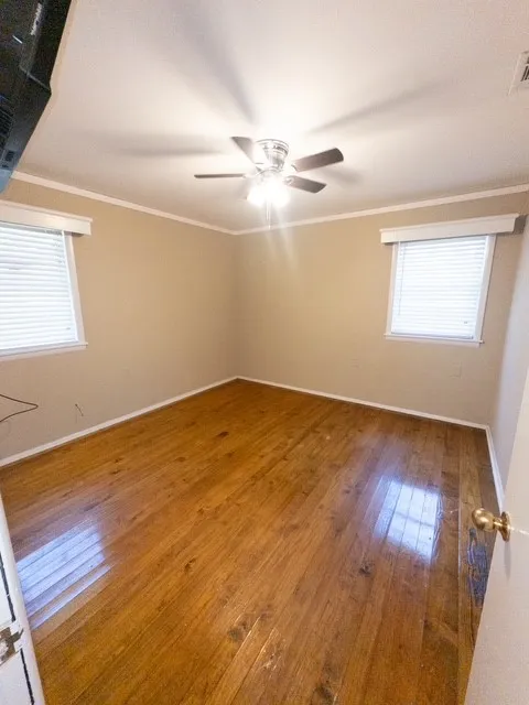 Room featuring wood-finish flooring, light-toned wall paint, and white trim