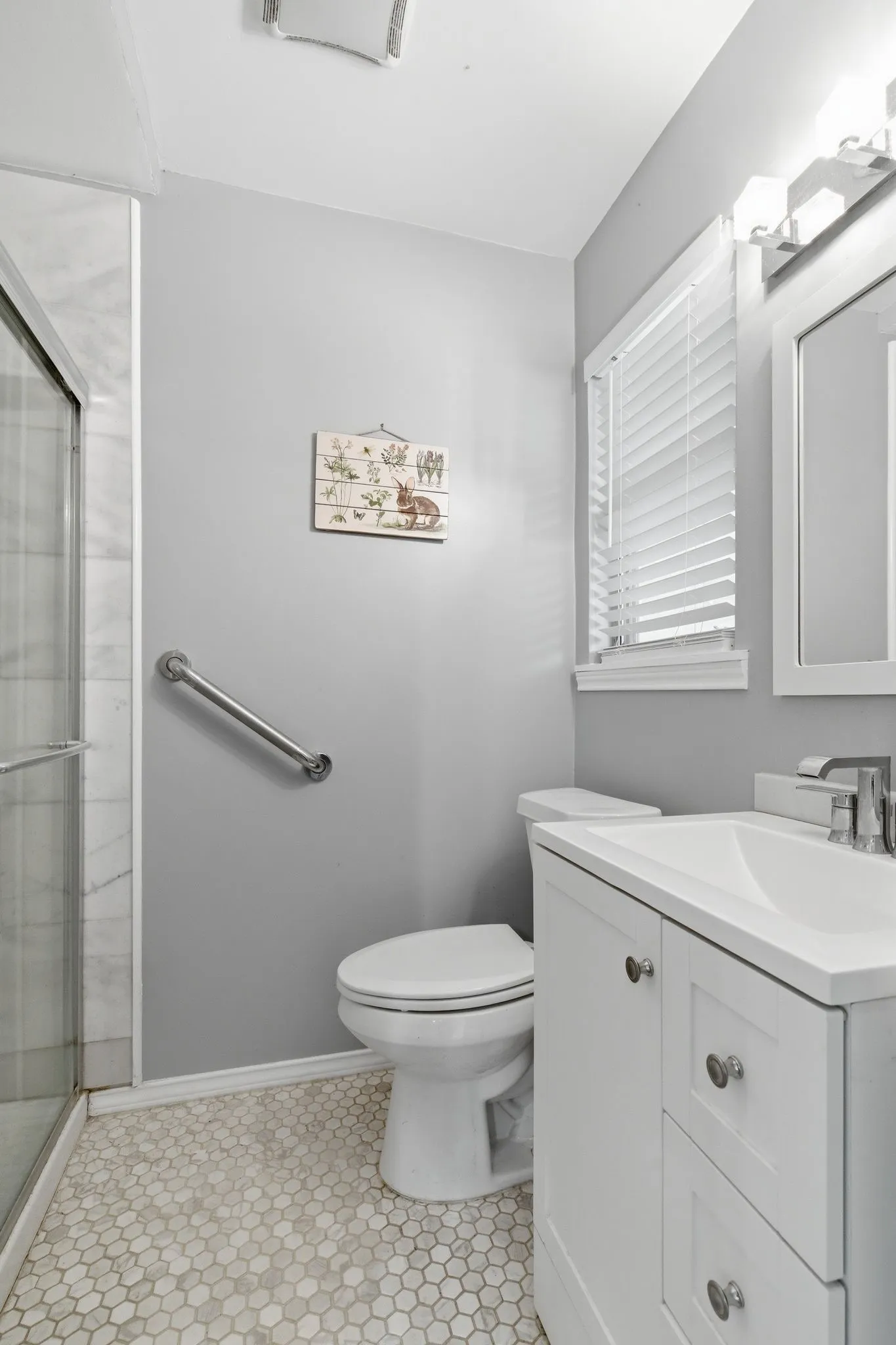 Bathroom featuring a glass-enclosed shower with subway tile, hexagonal floor tiles, a white vanity with a rectangular sink, and a toilet