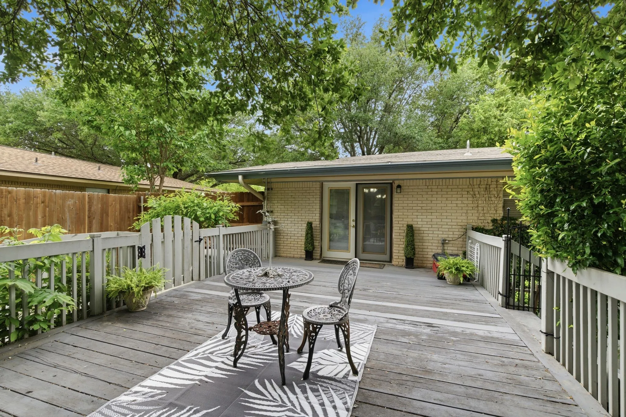 Spacious outdoor deck featuring gray wood planks and a painted railing system