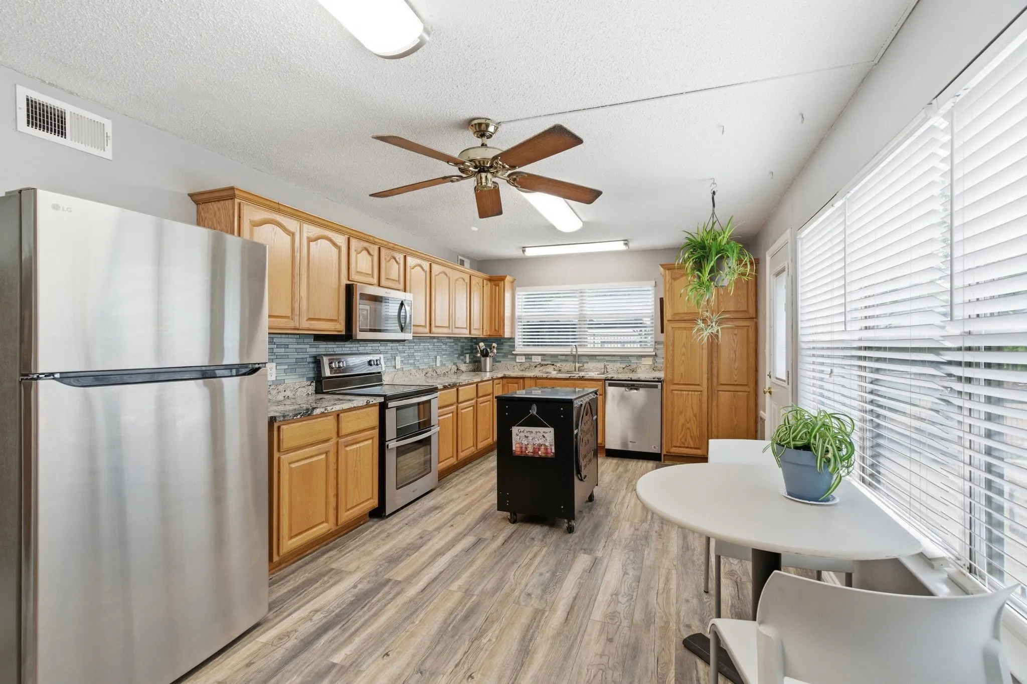 Kitchen with wood-finish flooring, light wood cabinetry, stainless steel appliances, and extensive counter space