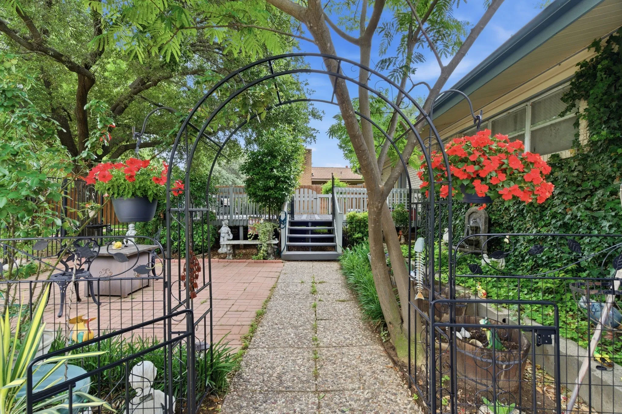 Landscaped backyard featuring a stone pathway, brick patio, and tiered wood decking