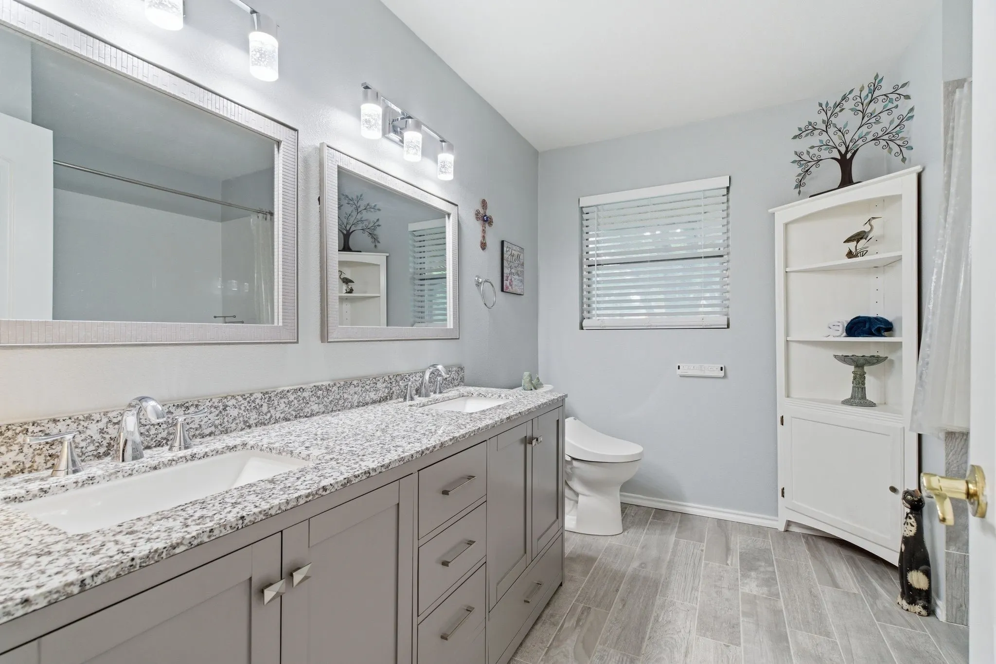 Bathroom featuring a double vanity with stone-finish countertop, dual undermount sinks, and contemporary faucets