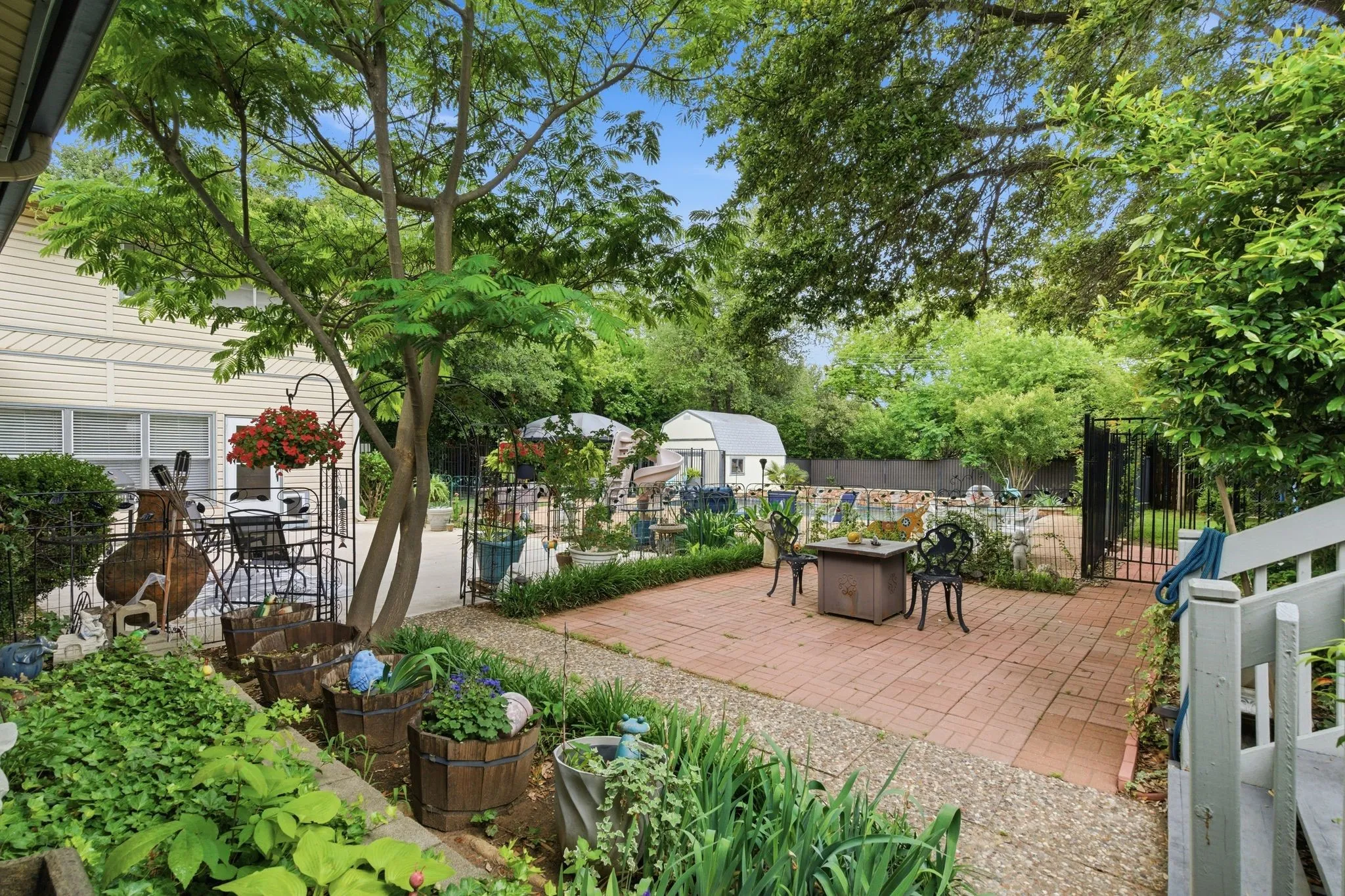 Expansive outdoor area featuring a brick paver patio, gravel pathways, and mature trees