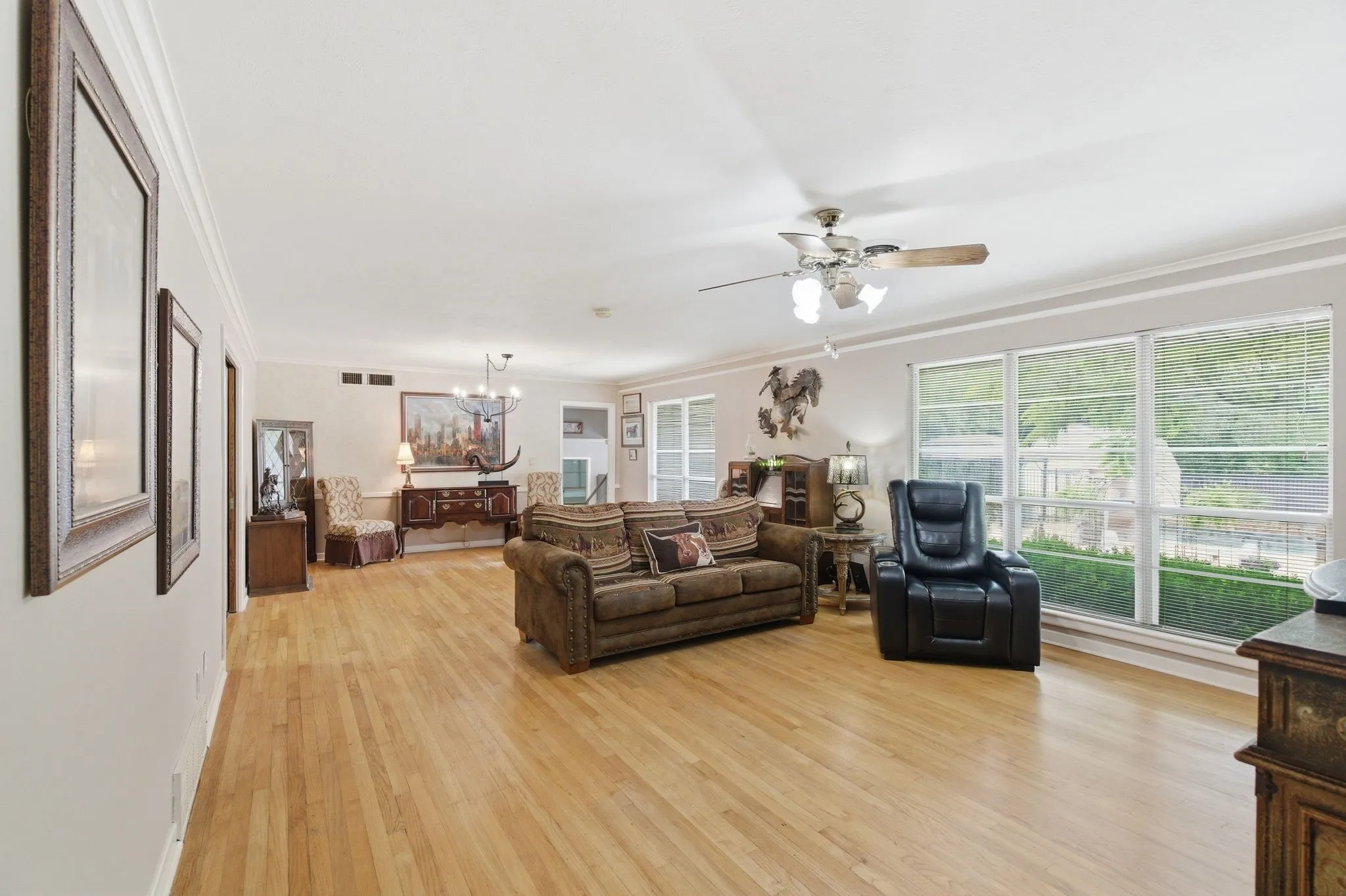 Expansive interior room featuring light wood-finish flooring, a multi-pane window wall, and crown molding