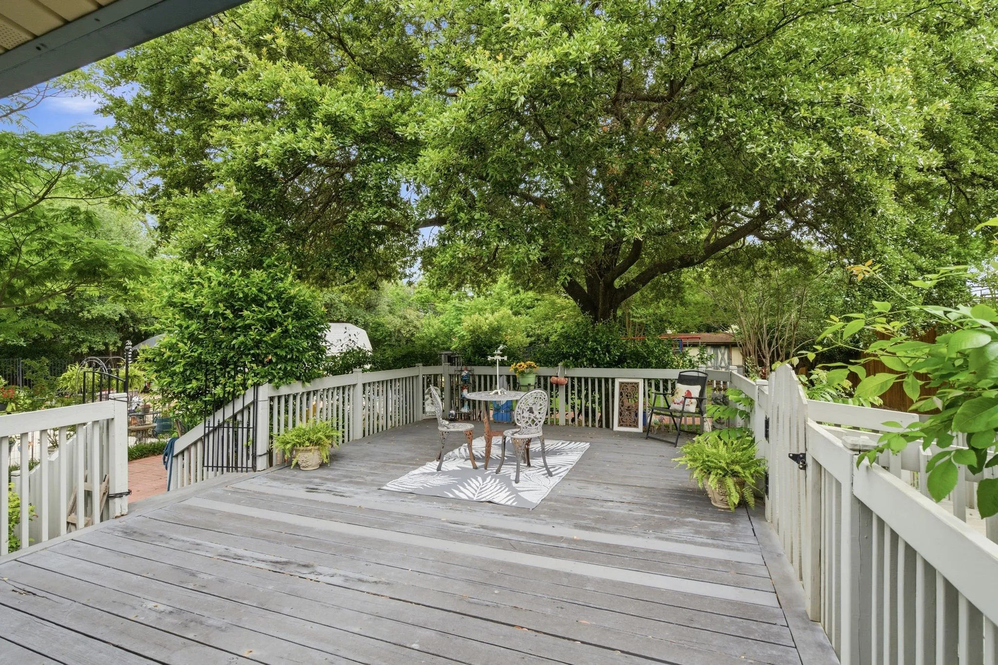 Spacious outdoor deck with gray wood plank flooring, white railing, and a private gate