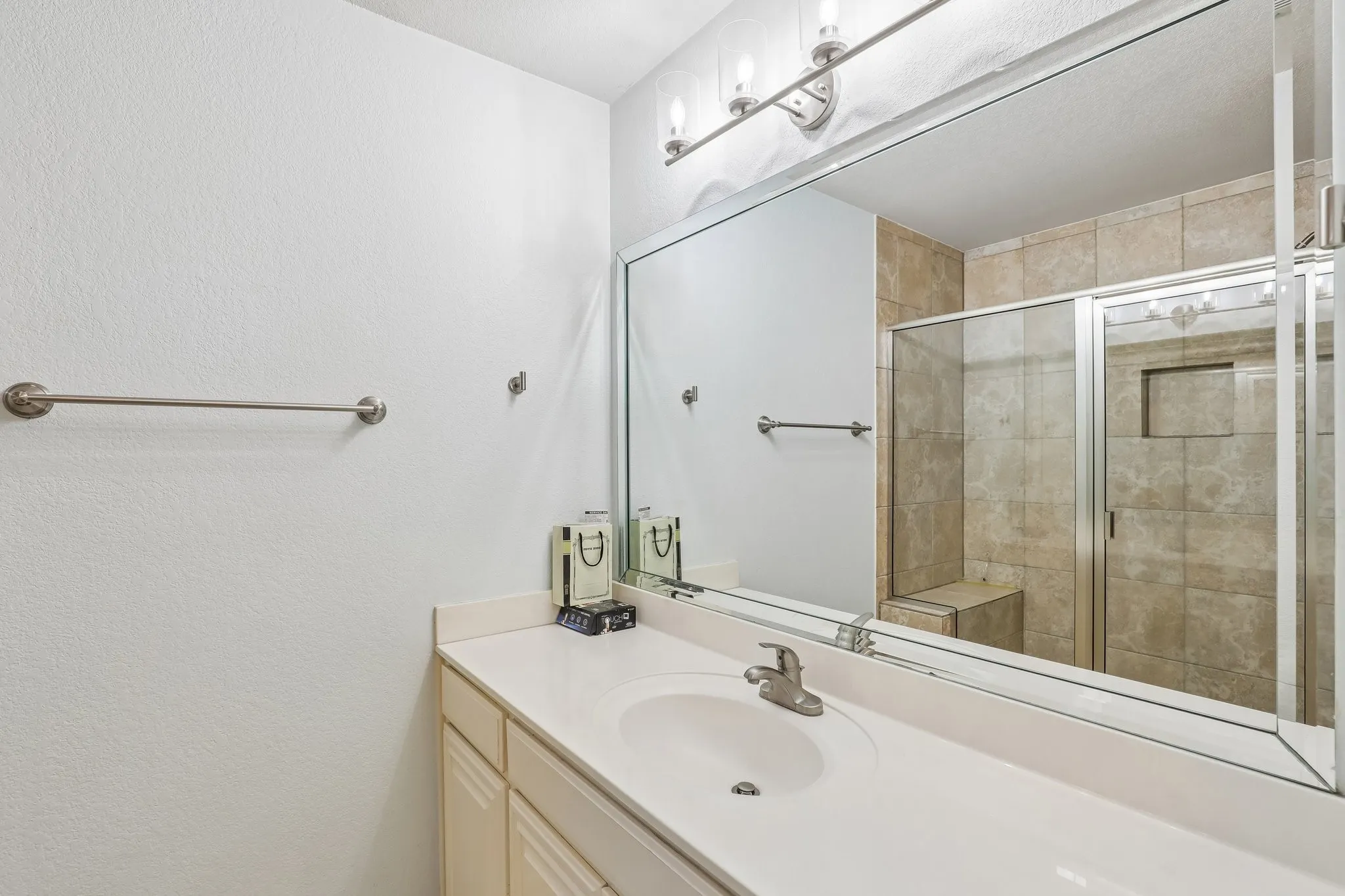 Bathroom vanity with an integrated sink, brushed nickel faucet, and a large wall-mounted mirror