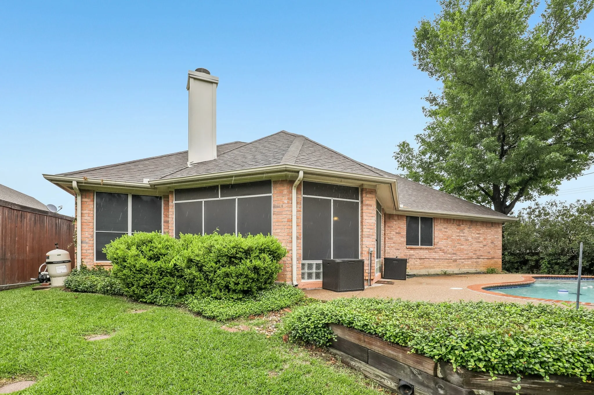 Brick exterior with a gabled roofline, a screened-in porch, and an in-ground swimming pool