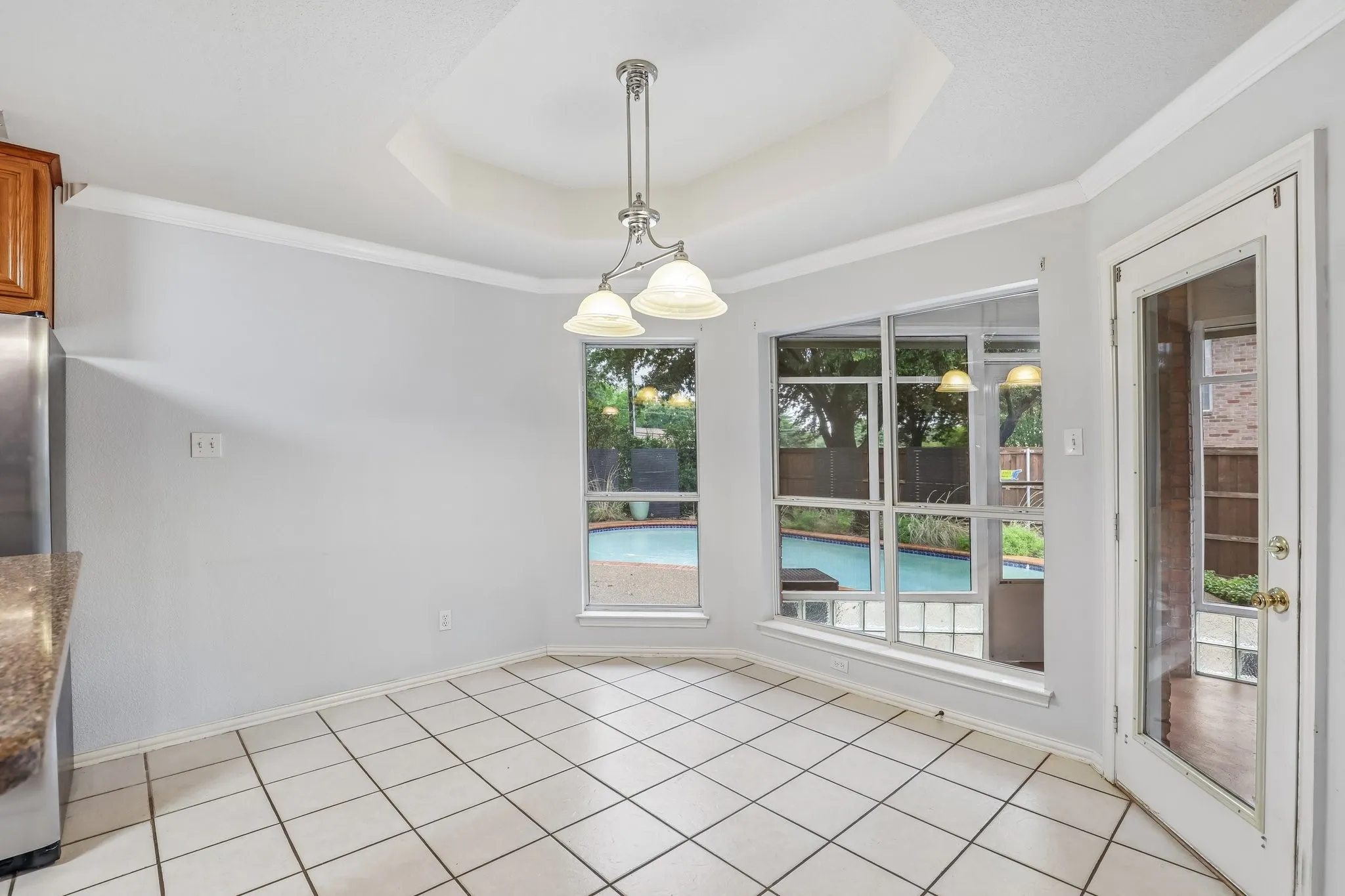 Dining area with white tile flooring and a tray ceiling