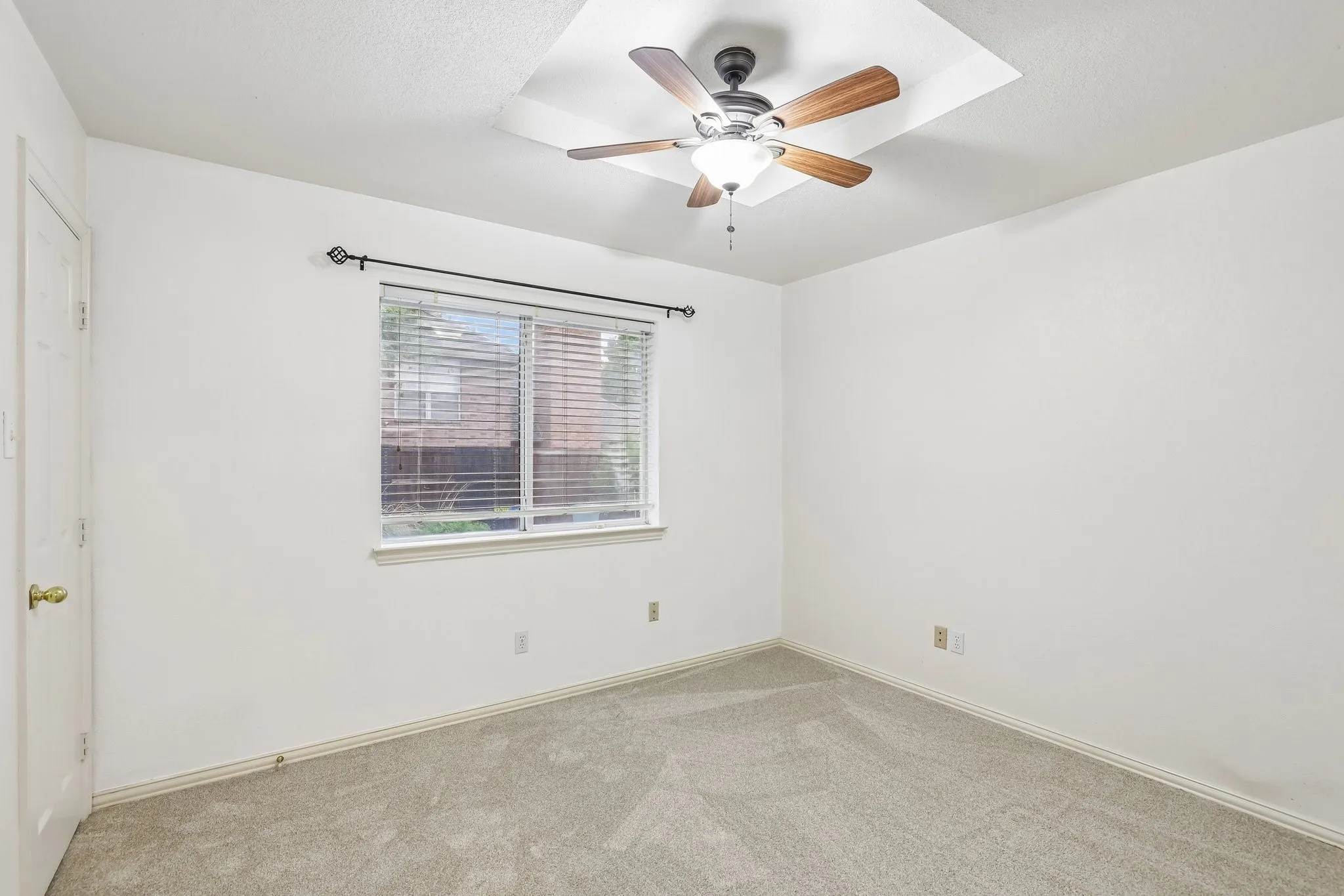 Bright room featuring neutral-toned carpet, white walls, and a window with blinds