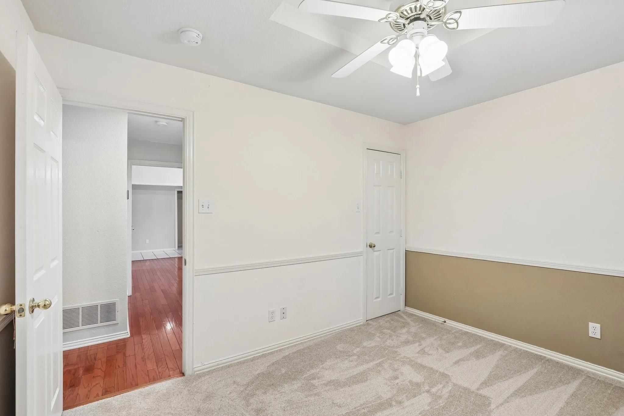 Carpeted room with a ceiling fan light fixture