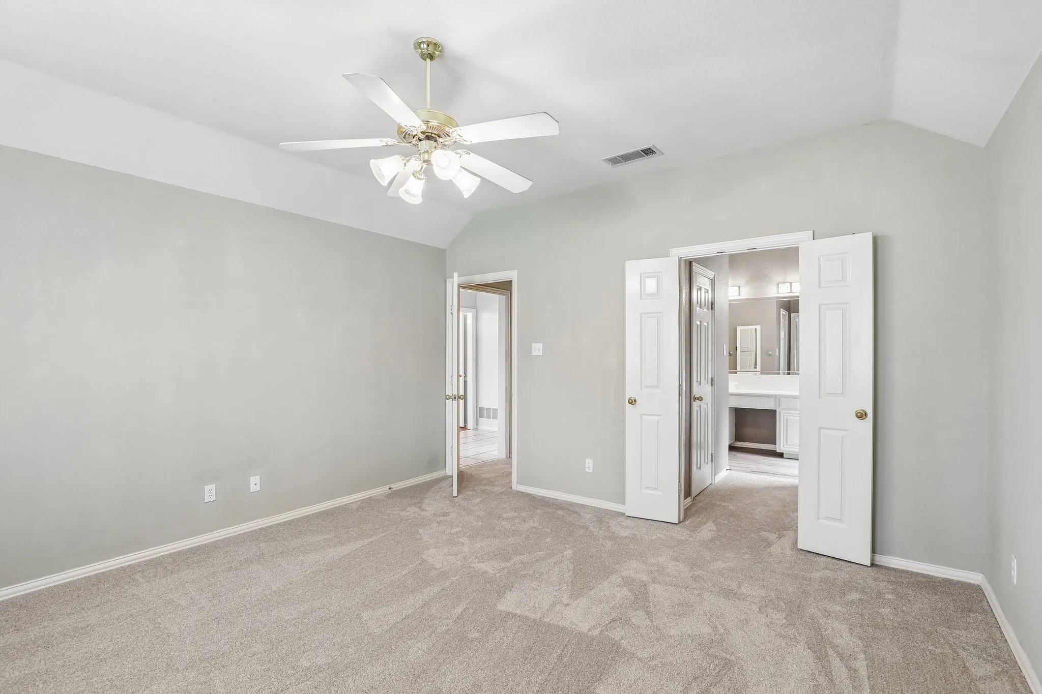 Spacious room featuring vaulted ceilings, light gray walls, and plush carpeting