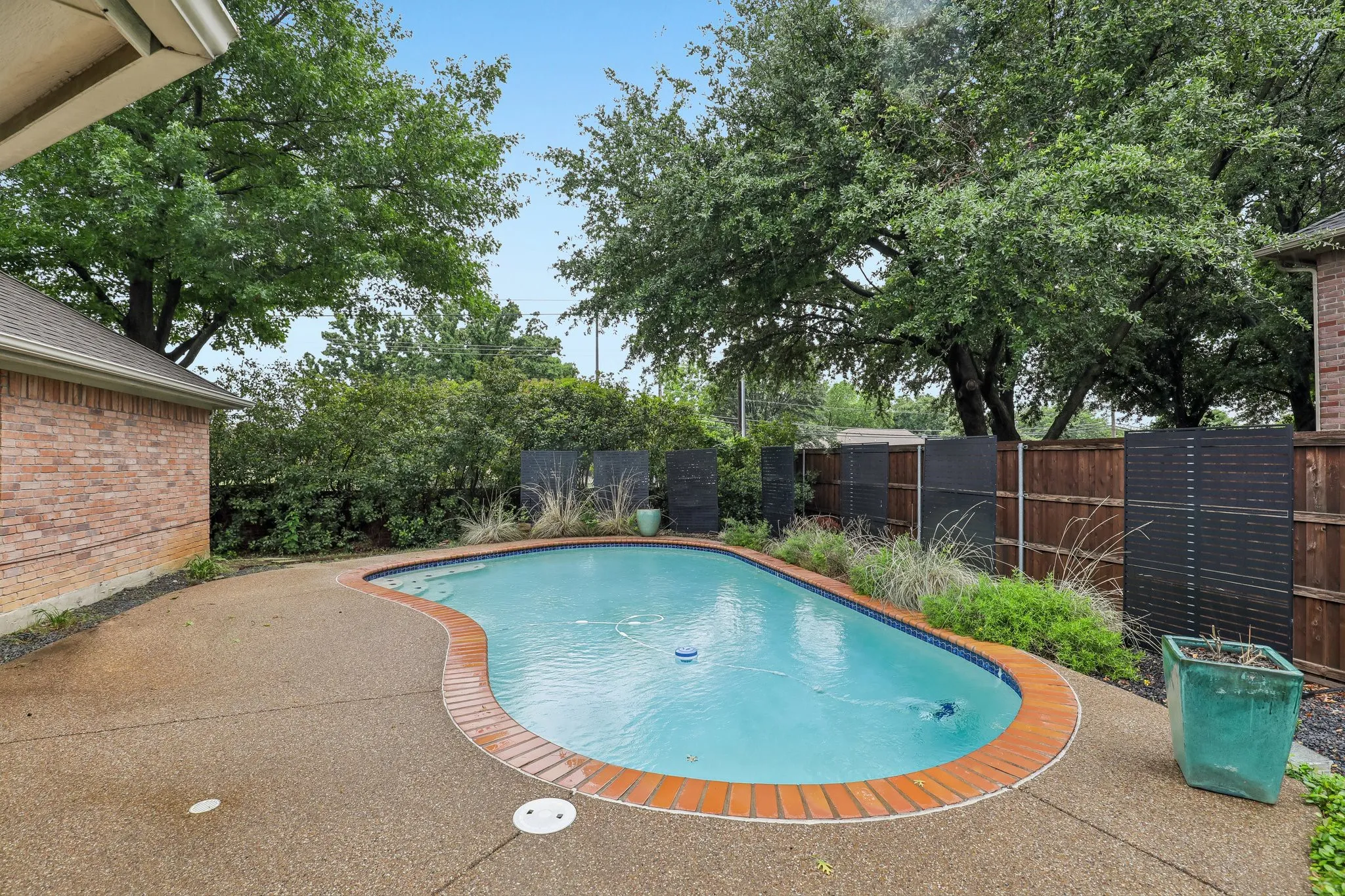 Freeform pool with brick coping and exposed aggregate decking