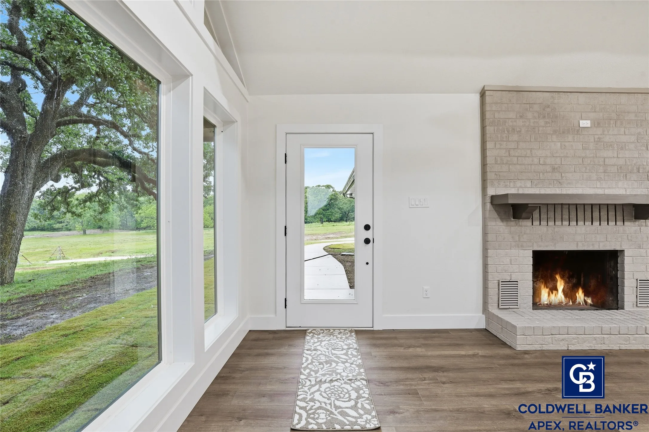 Step inside to an impressive open-concept living area with soaring vaulted ceilings, exposed beams, and a dramatic wood-burning fireplace.