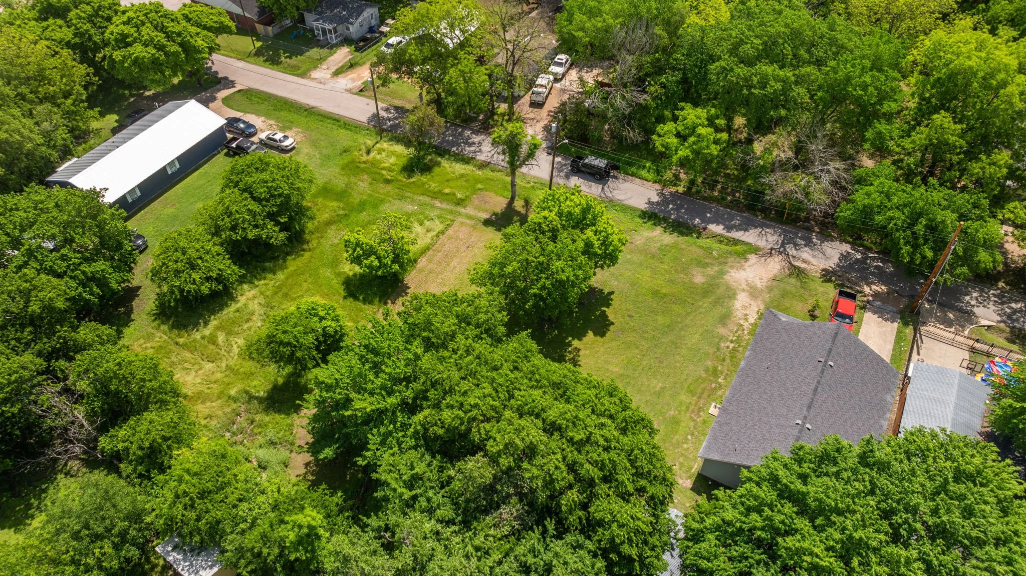 Expansive property featuring two distinct structures, mature trees, and substantial green space