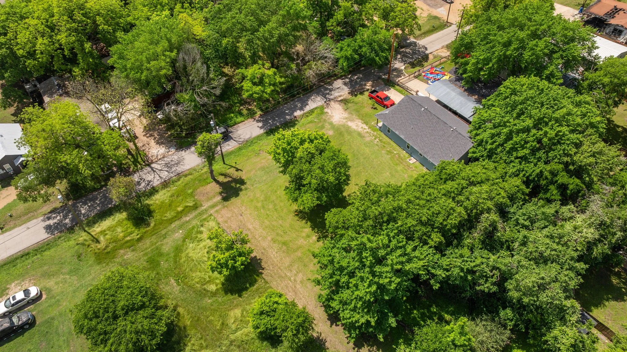 Aerial view showcasing a residential property with a dark shingle roof and a detached carport