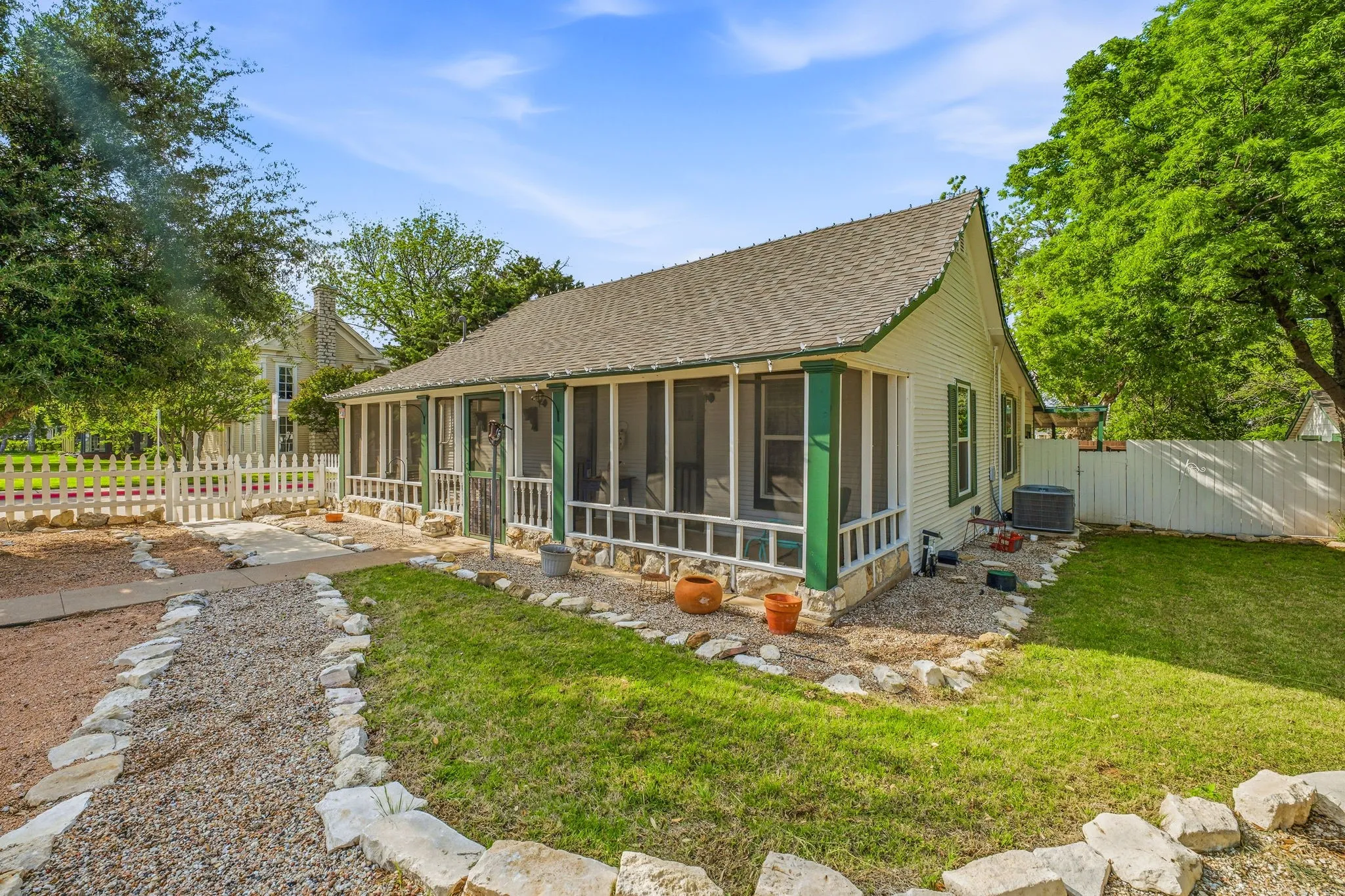 Home exterior featuring a screened-in porch, white picket fence, and a gravel pathway
