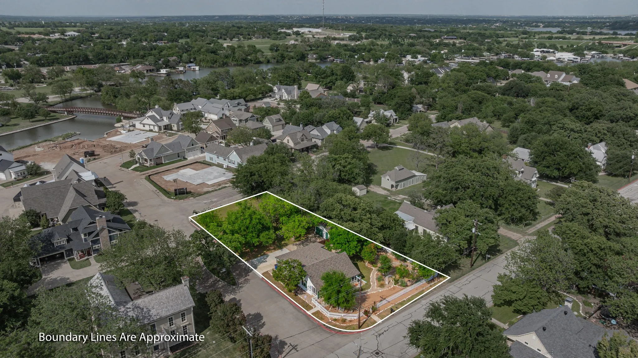 Aerial view of a residential property with established trees and a paved driveway, surrounded by a verdant landscape