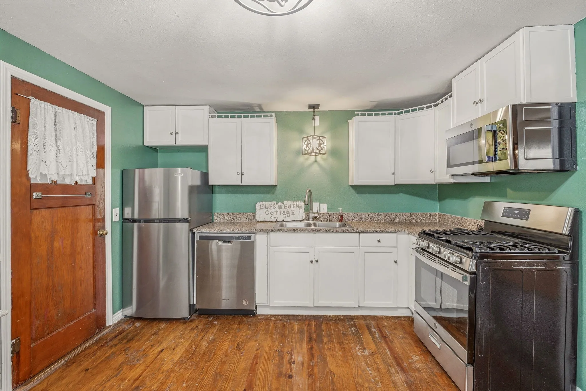 Kitchen featuring white cabinetry, light-toned countertops, and stainless steel appliances including a refrigerator, dishwasher, and range