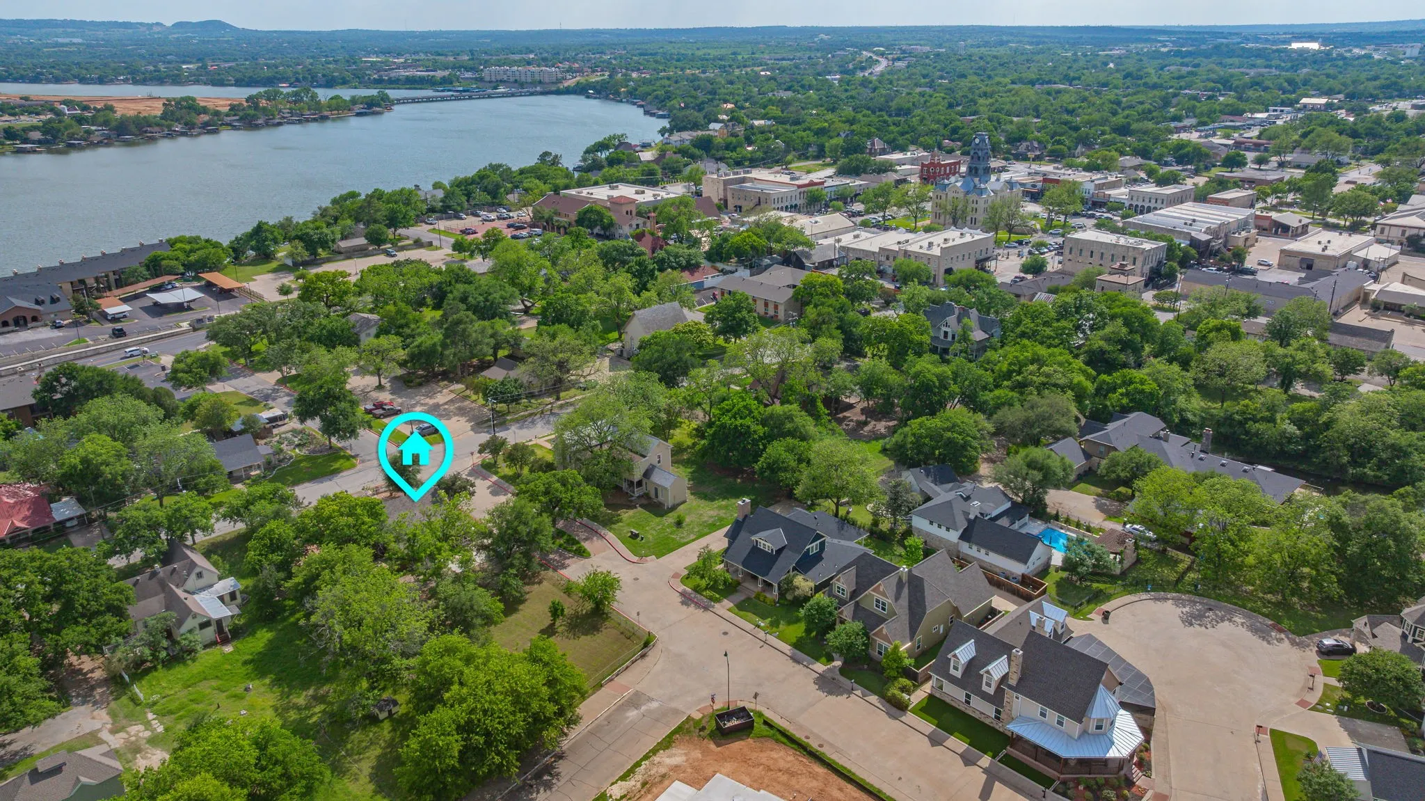 Aerial perspective showcasing proximity to waterfront, surrounding mature trees, and nearby urban architecture
