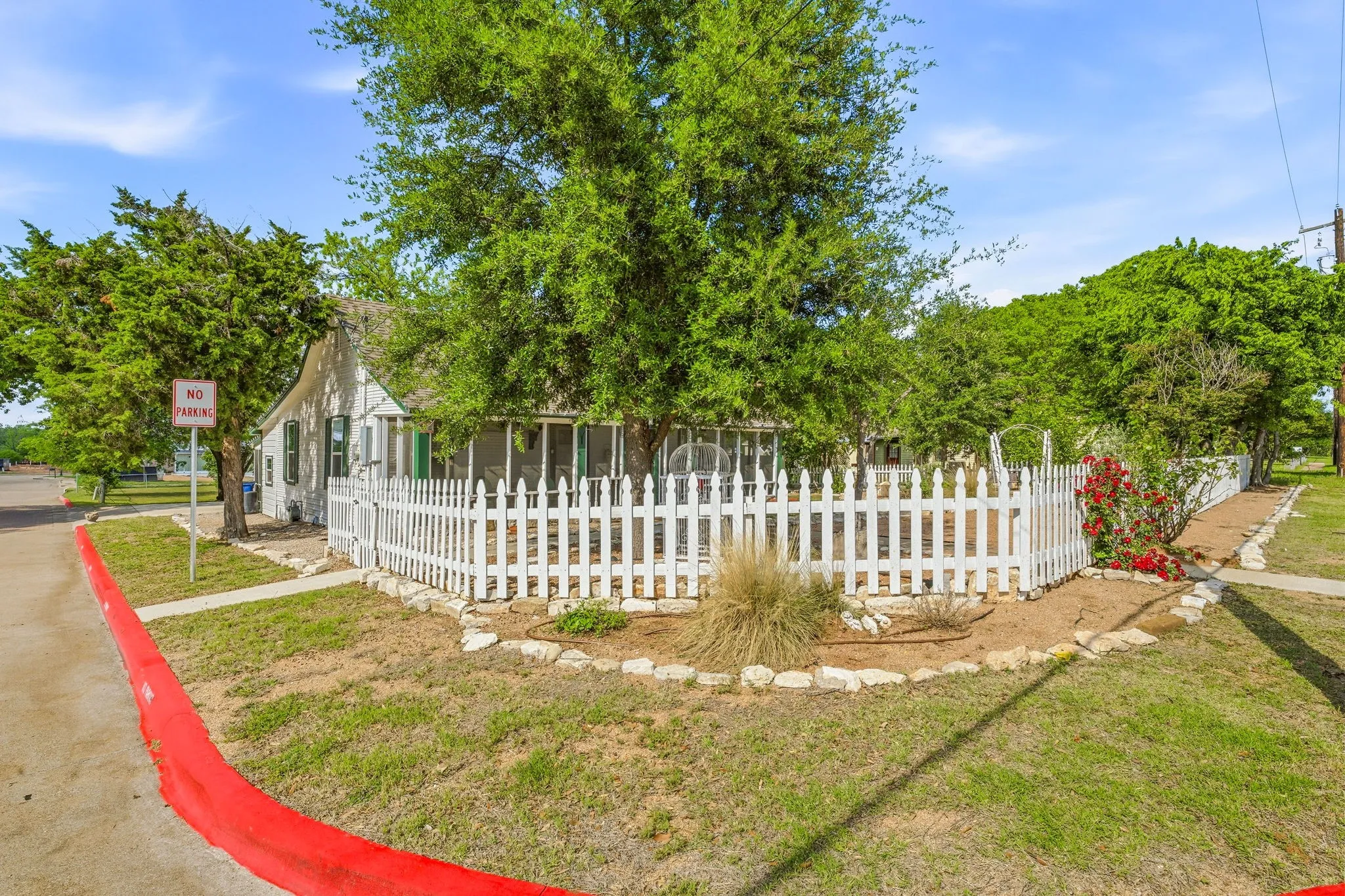 White picket fence encompassing the front yard with mature trees