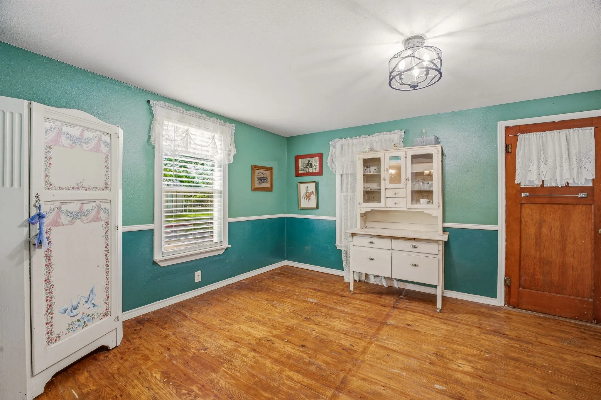 Spacious room featuring wood-finish flooring, two-tone painted walls, and a ceiling-mounted light fixture