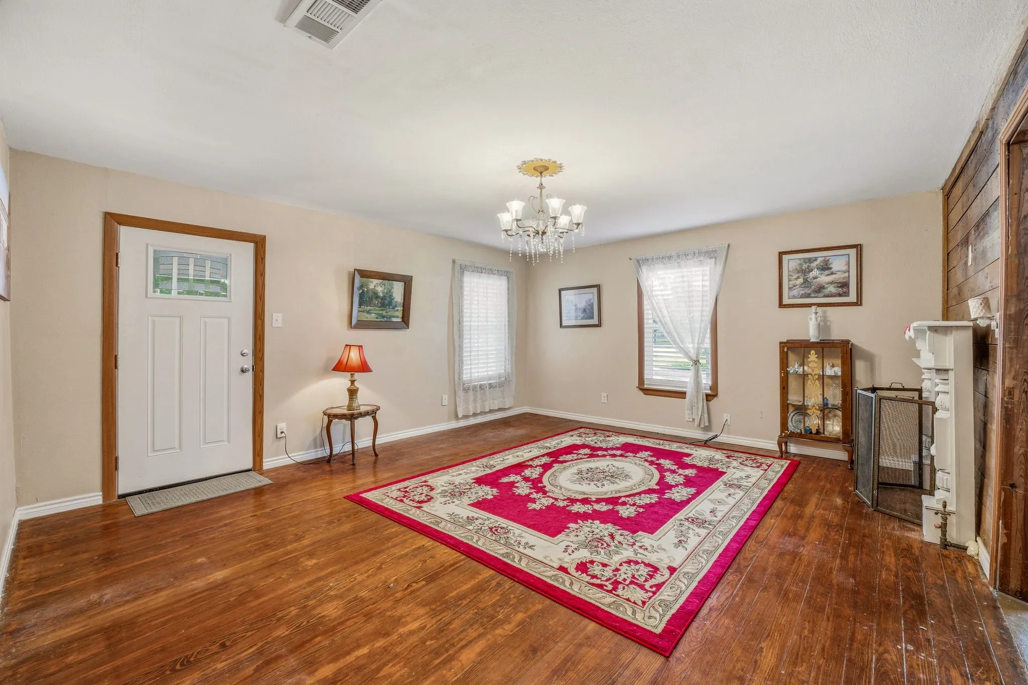 Living area featuring wood-finish flooring, a decorative chandelier, and a white entry door with a window pane