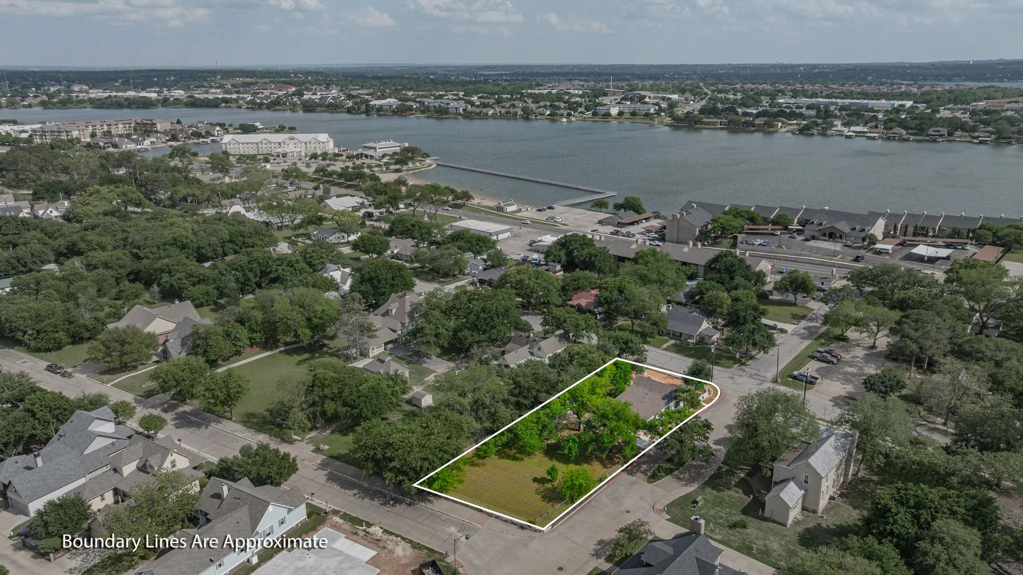 Aerial perspective showcasing a property outlined in white, set amidst a neighborhood with mature trees