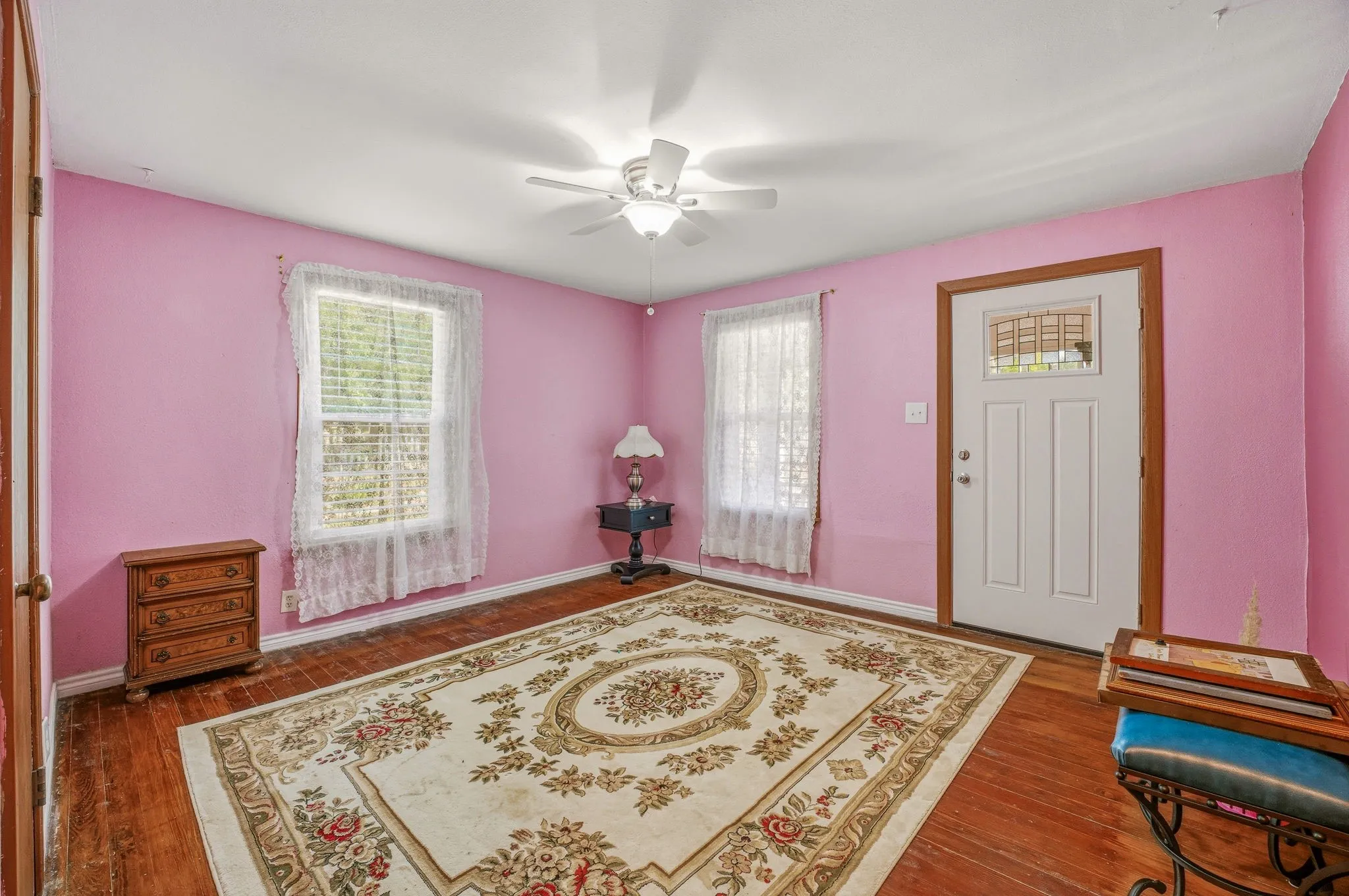 Interior space featuring wood-finish flooring, two windows, and a ceiling fan with integrated lighting