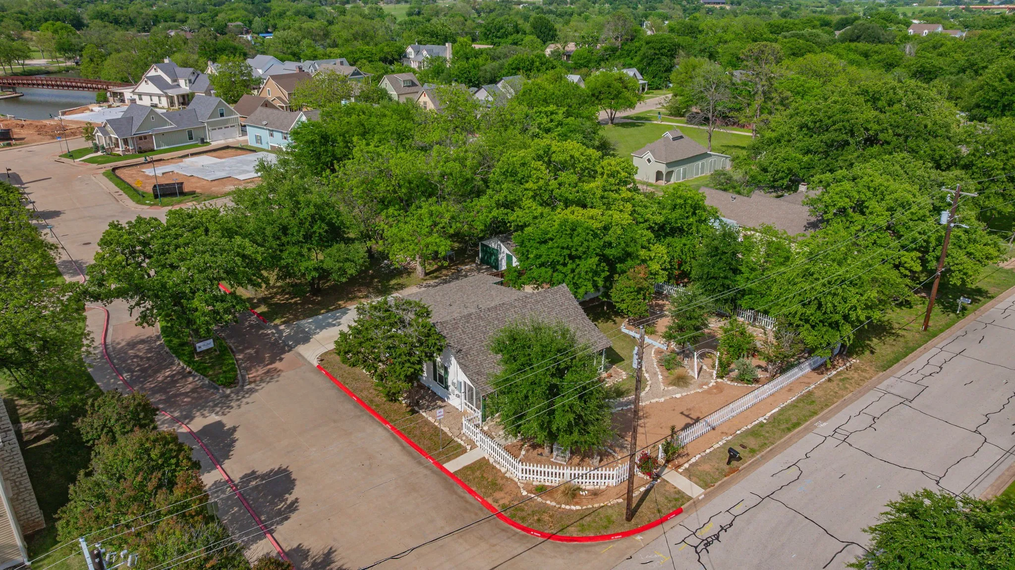 Aerial perspective showcasing a property with a white picket fence and established landscaping