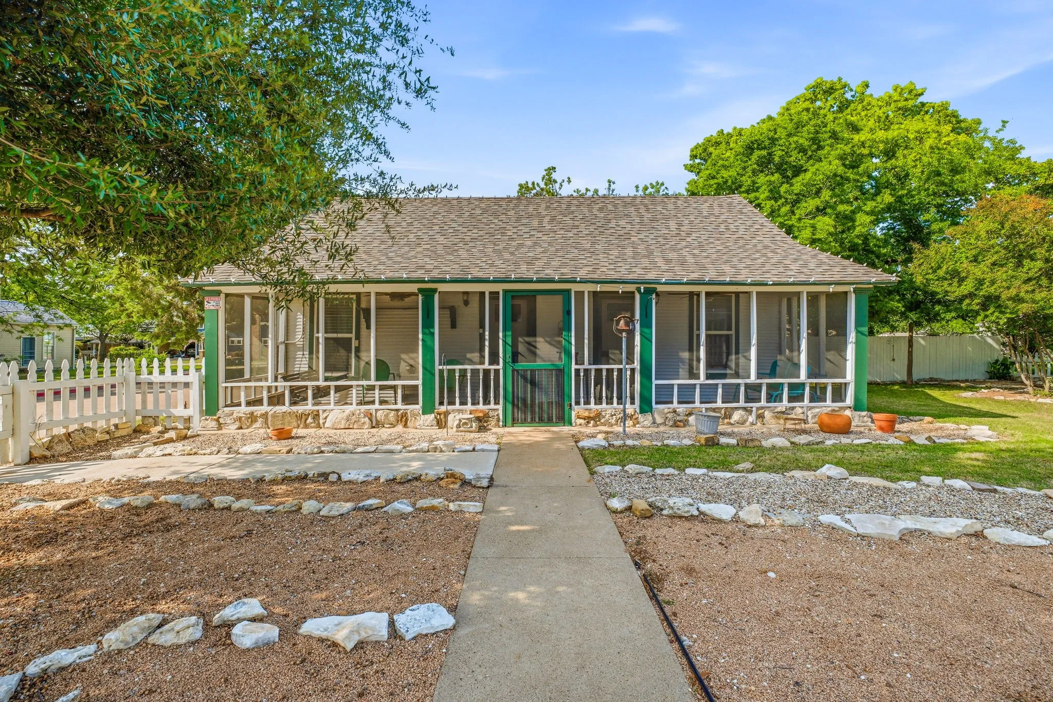 Cottage-style residence featuring a screened porch, gabled roofline, and stone veneer foundation