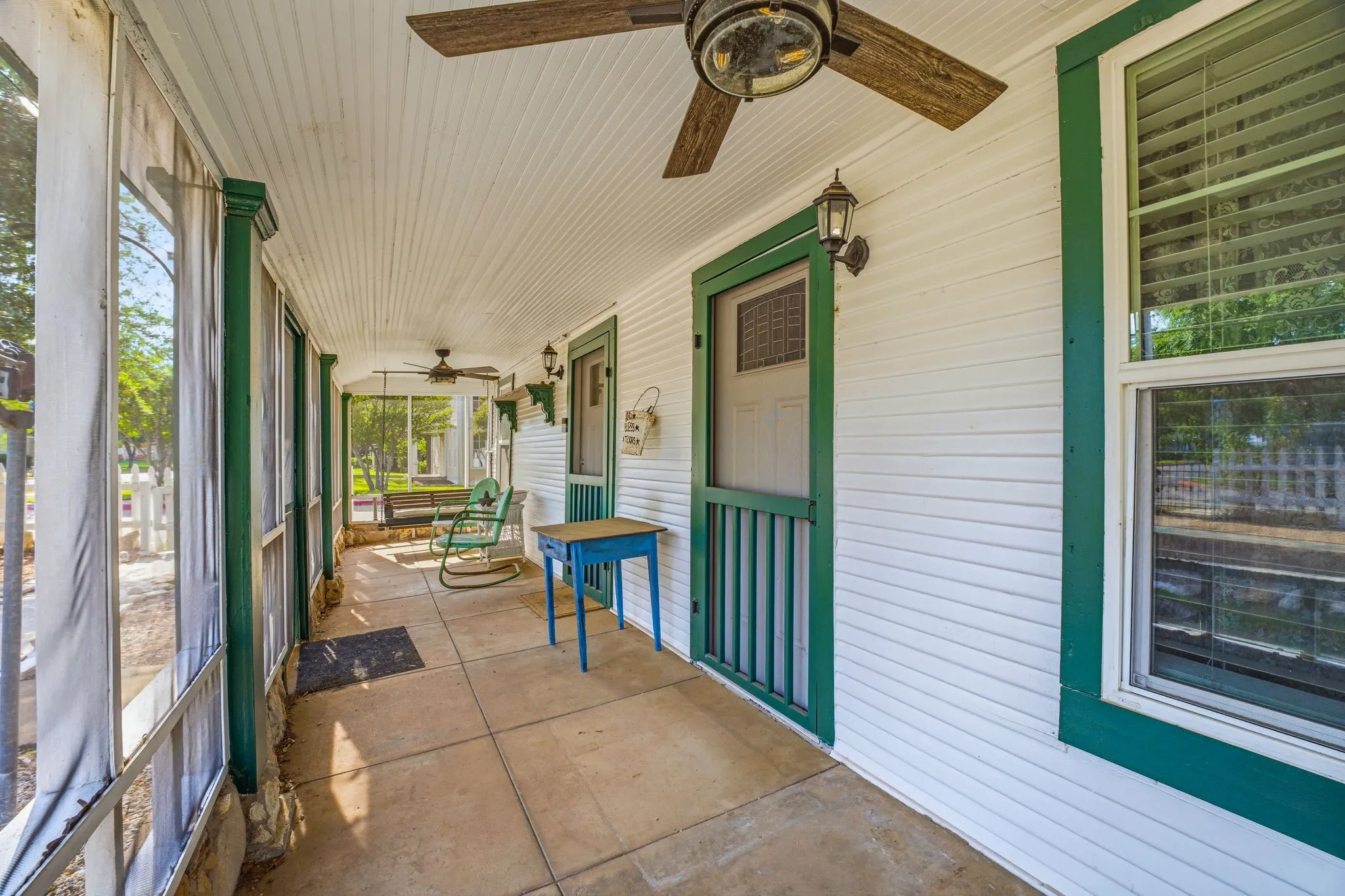 Expansive screened porch featuring a concrete slab floor, white plank ceiling, and dual ceiling fans